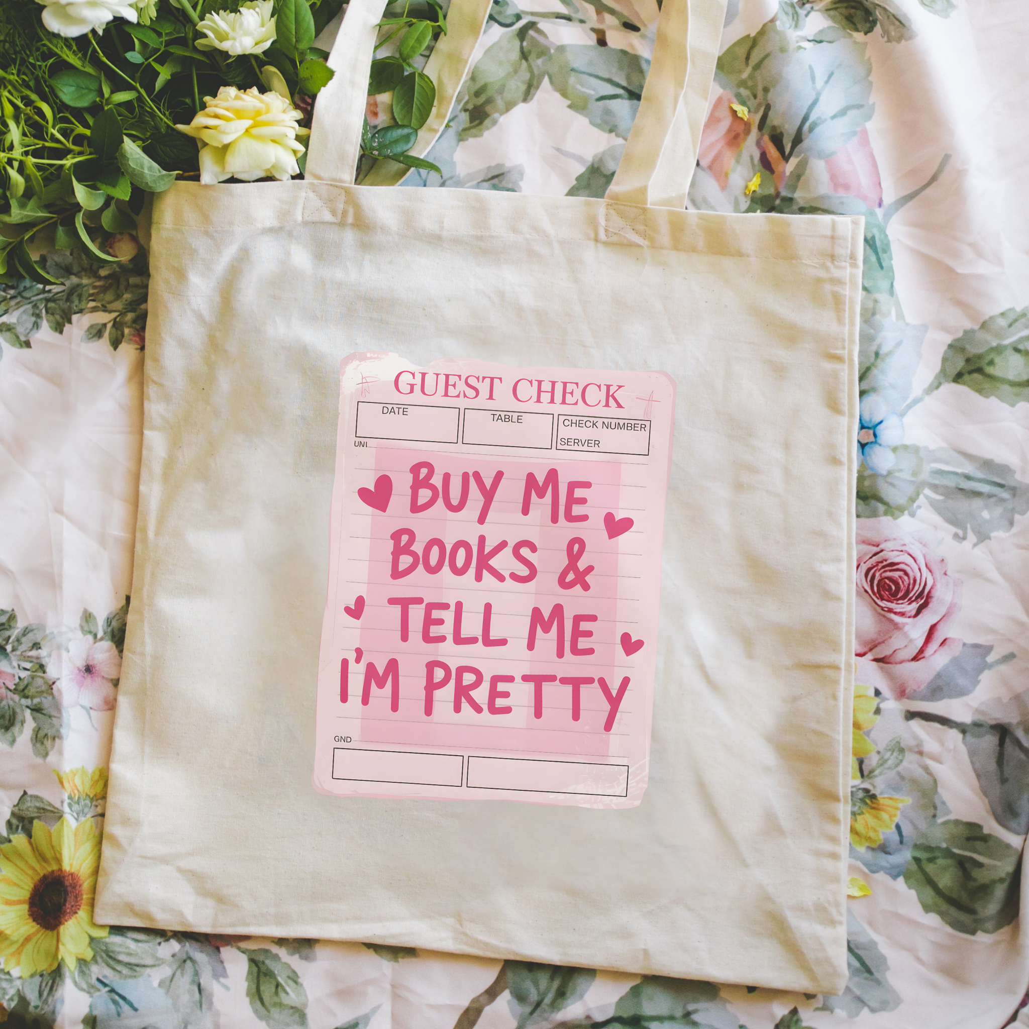 Bookish Tote bag with a pink sign and floral arrangement on a pink surface, Buy Me Books and Tell Me I'm Pretty
