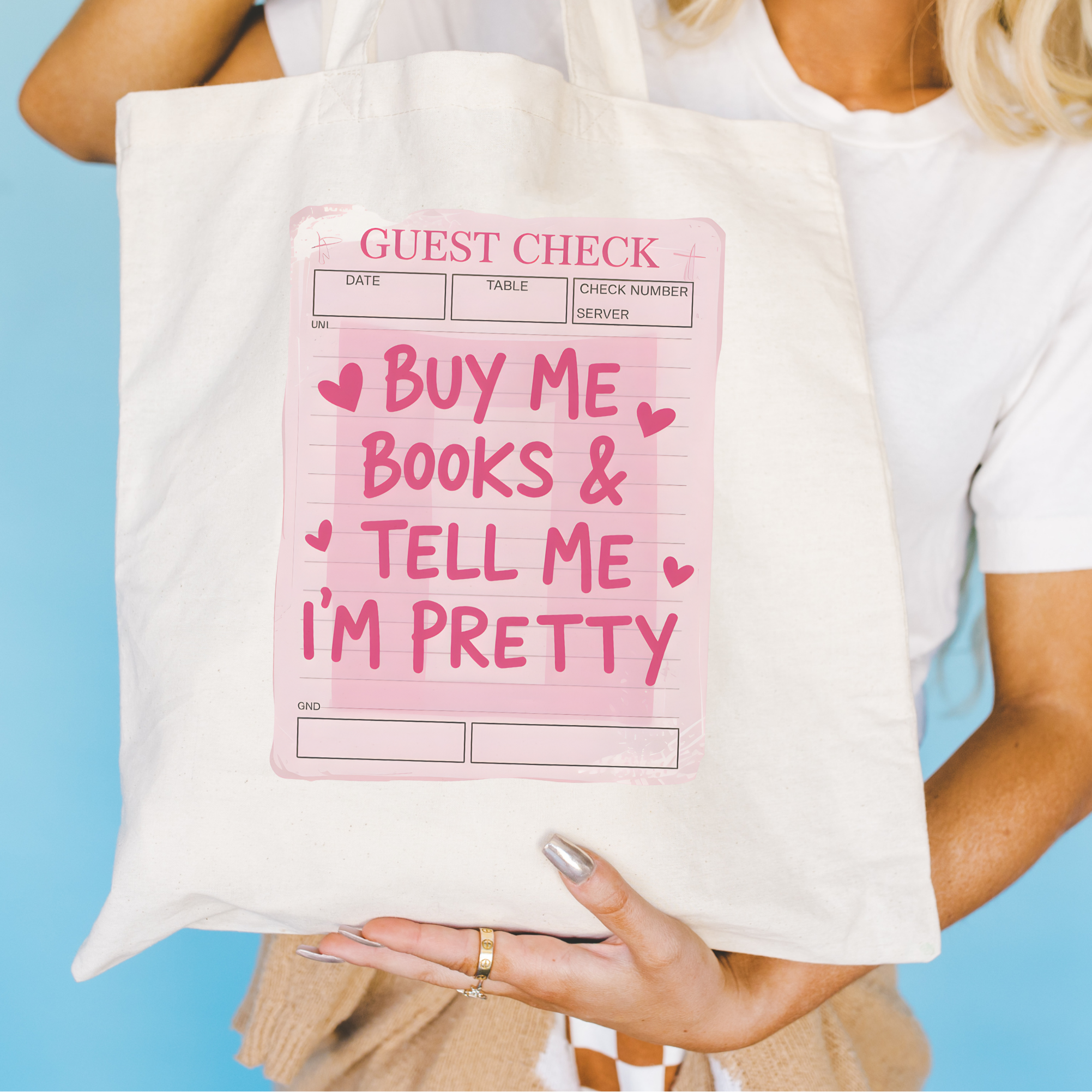 Bookish Tote bag with a pink sign and floral arrangement on a blue surface, Buy Me Books and Tell Me I'm Pretty