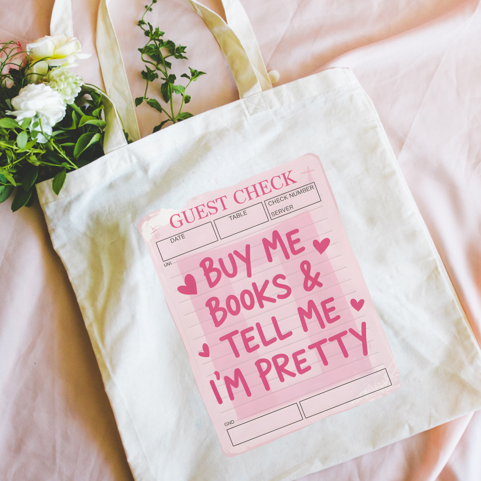 Bookish Tote bag with a pink sign and floral arrangement on a pink surface, Buy Me Books and Tell Me I'm Pretty