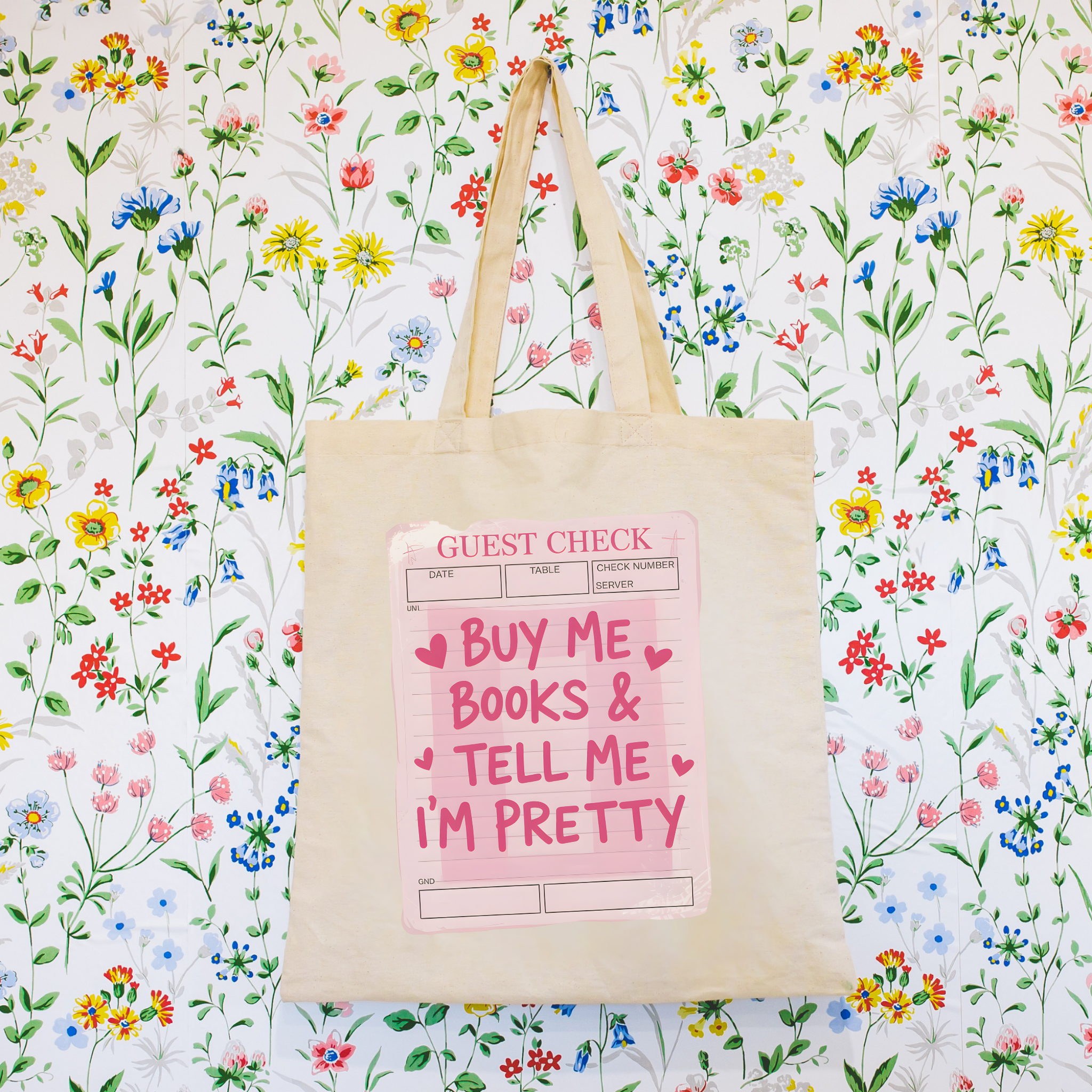 Tote bag with 'Buy Me Books & Tell Me I'm Pretty' design on a floral background