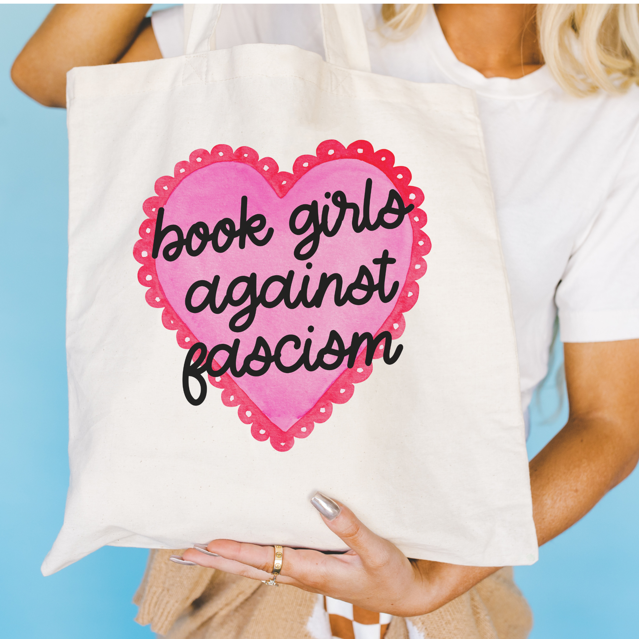 Bookish Tote bag with a pink heart and text held by a person against a blue background