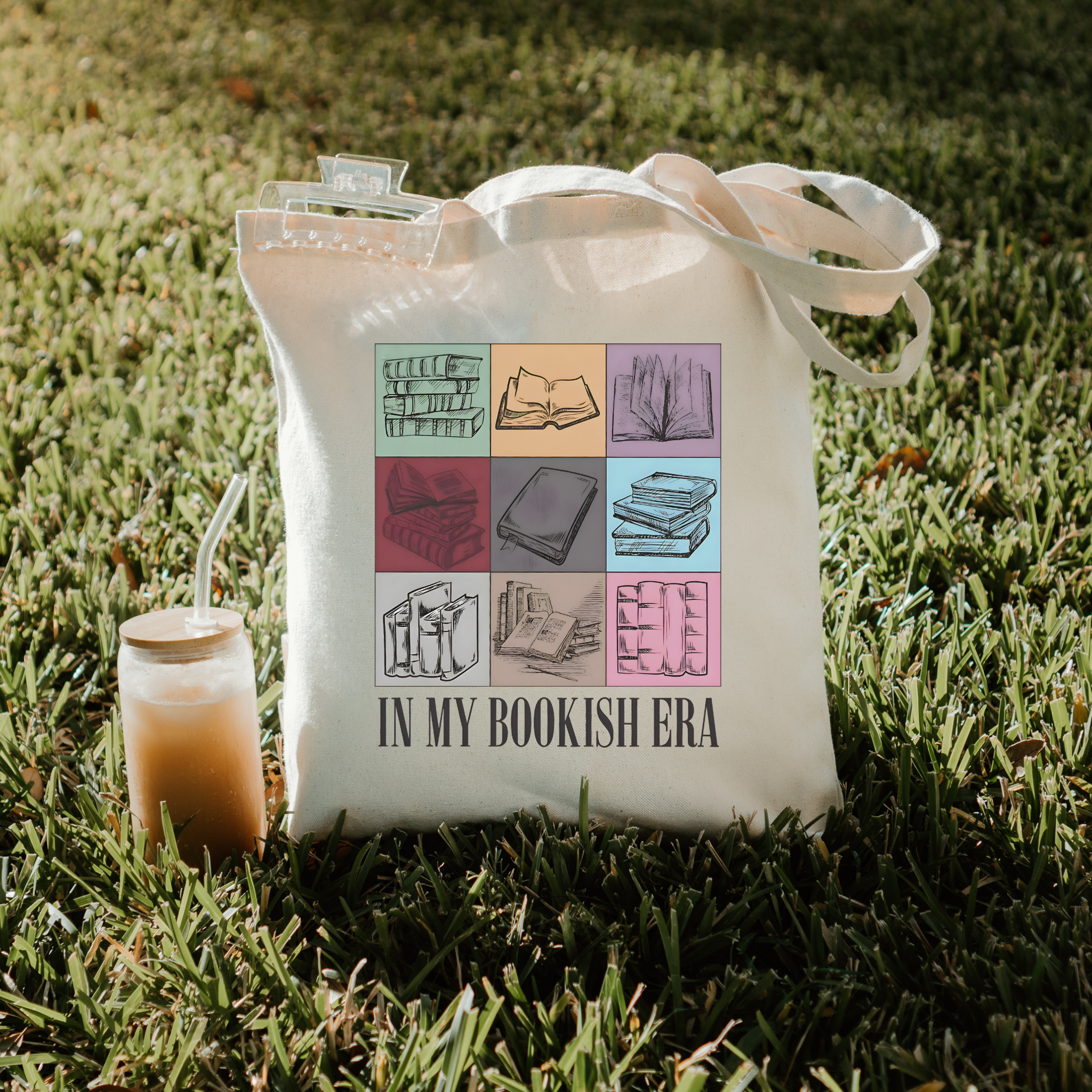 Tote bag with book-themed design and 'In My Bookish Era' text on grass