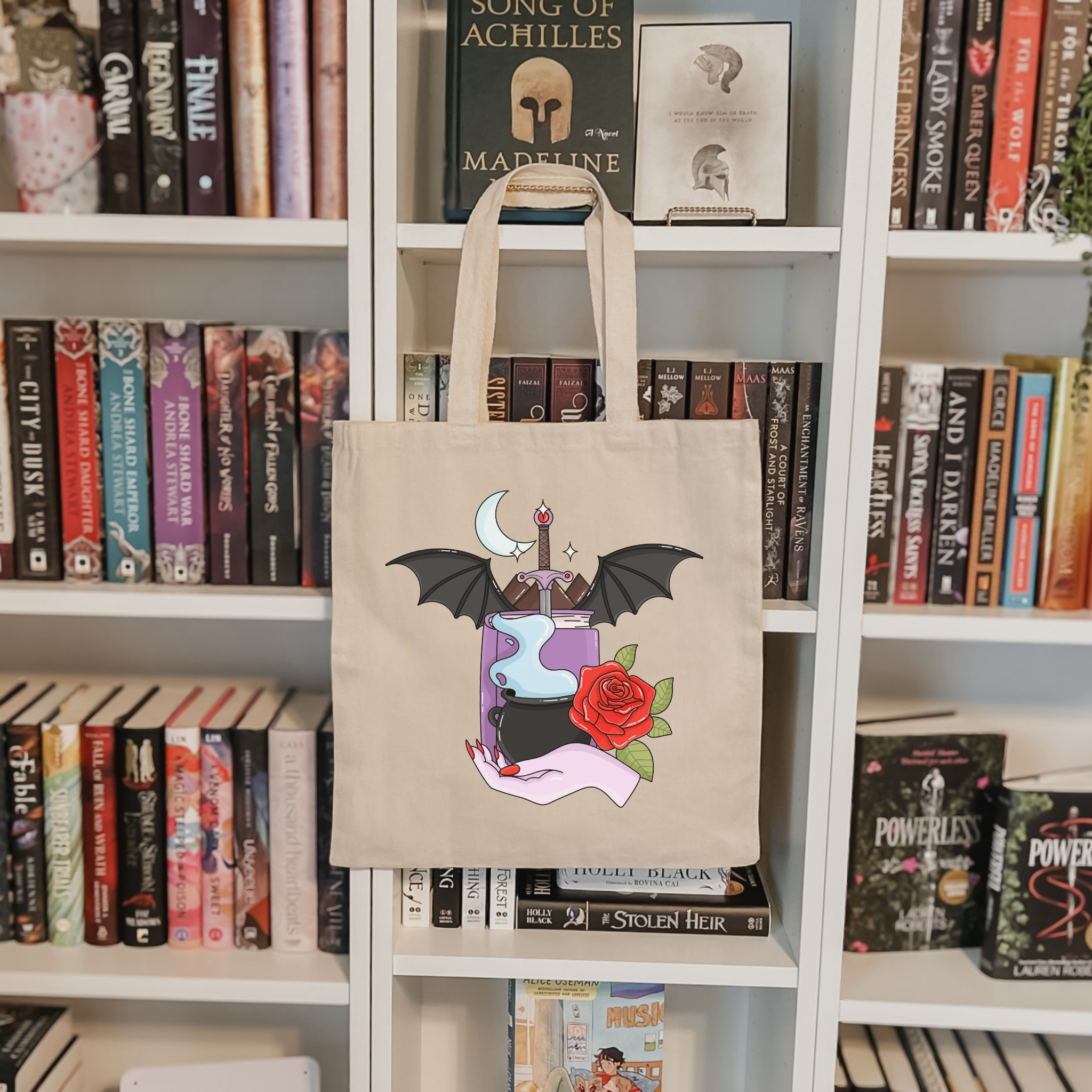 Bookish tote bag with a graphic design on a bookshelf filled with books.