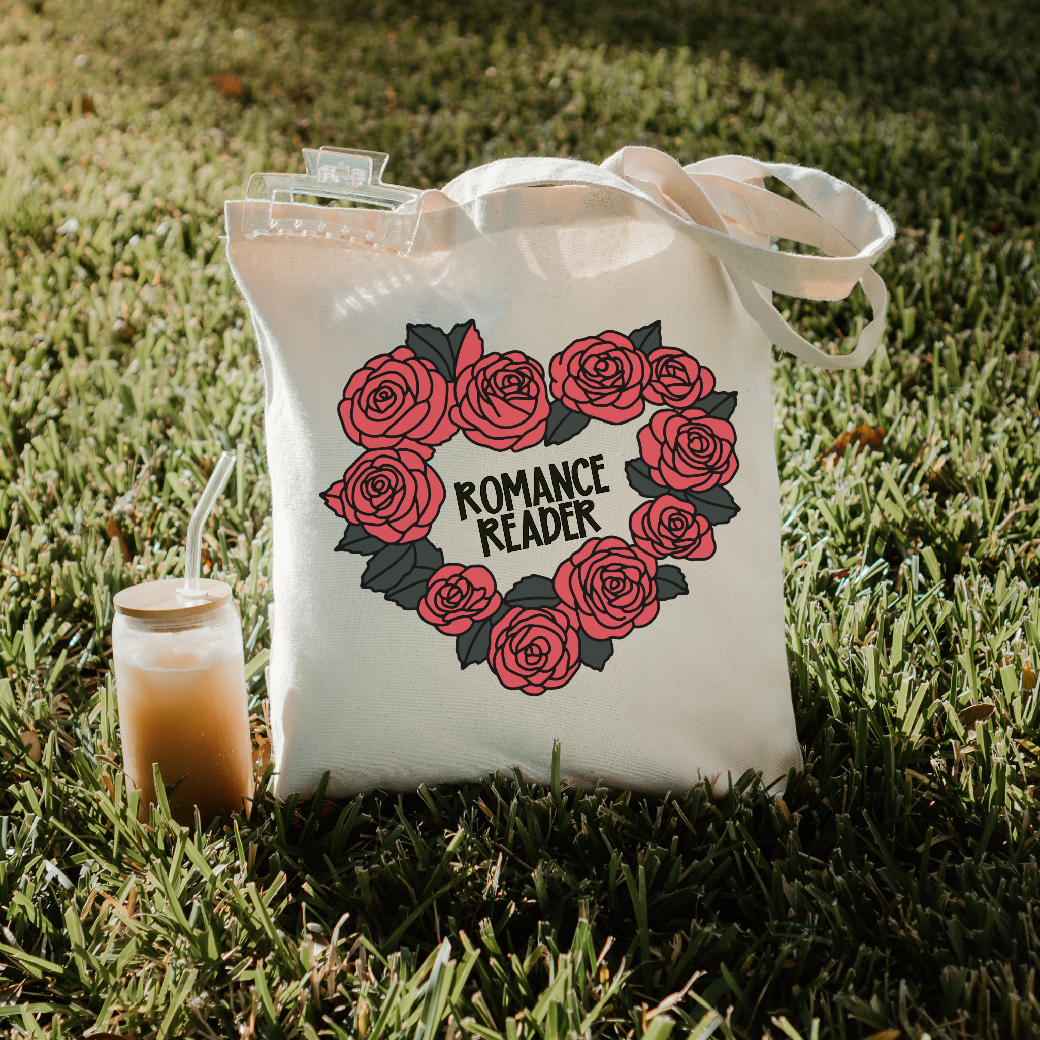 Tote bag with rose design and 'Romance Reader' text on grass