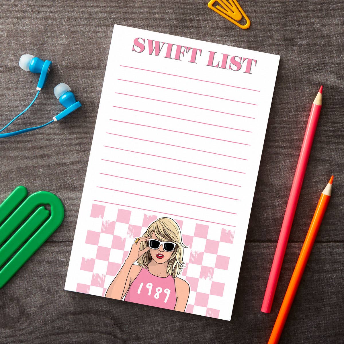 A pink notepad titled 'SWIFT LIST' with a checkered pattern and a cartoon image of a woman wearing sunglasses and a tank top with the text '1992' on it.