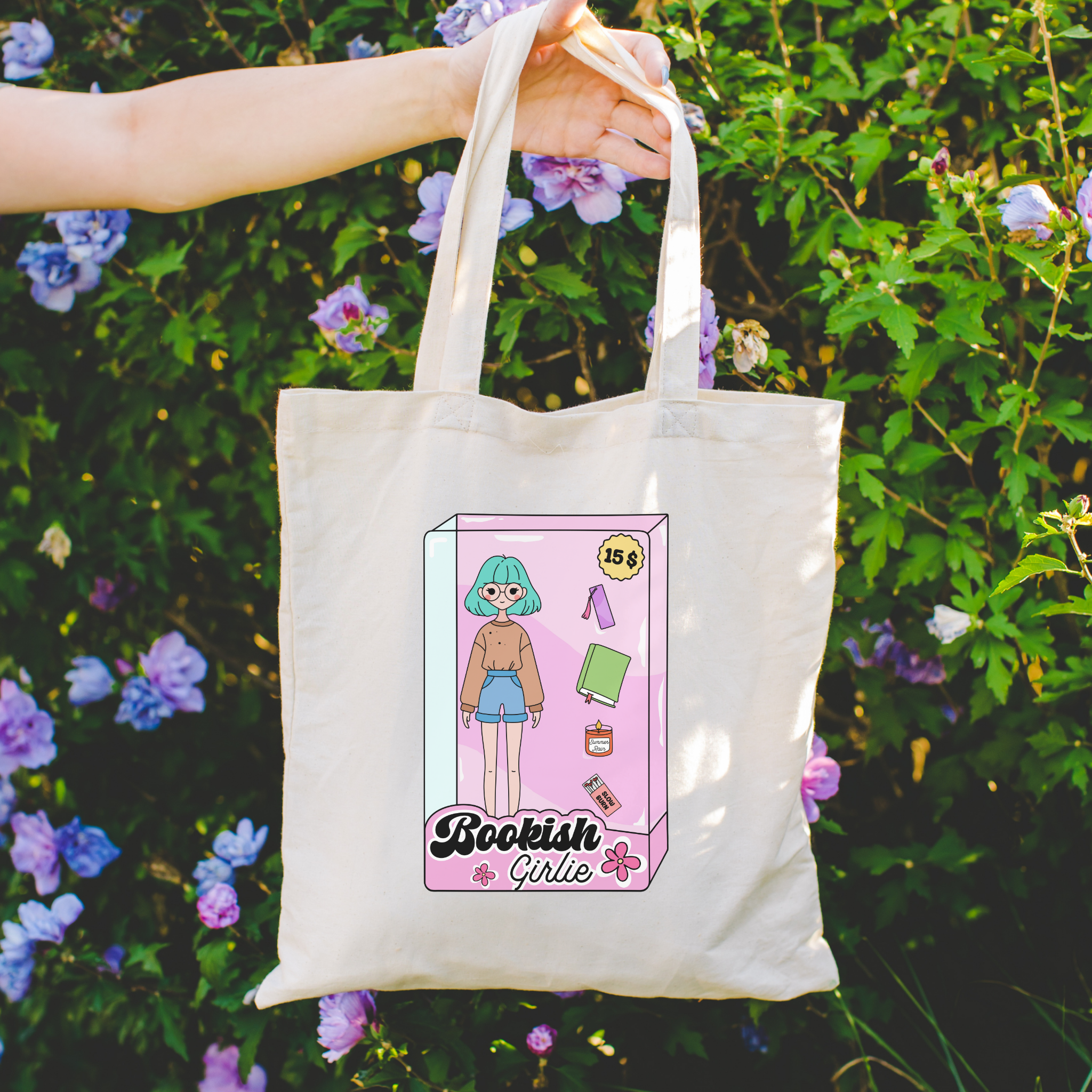 Tote bag with 'Bookish Girlie' design held in front of a floral background
