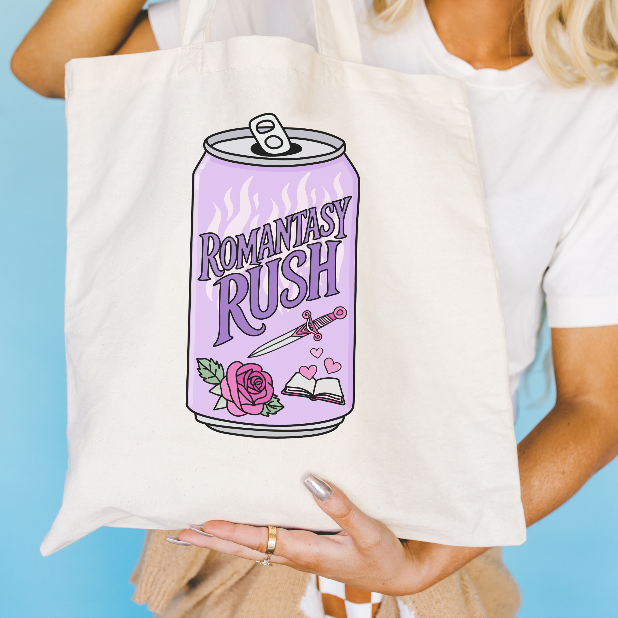 Bookish tote bag with 'Romantasy Rush' design held in front of a blue background