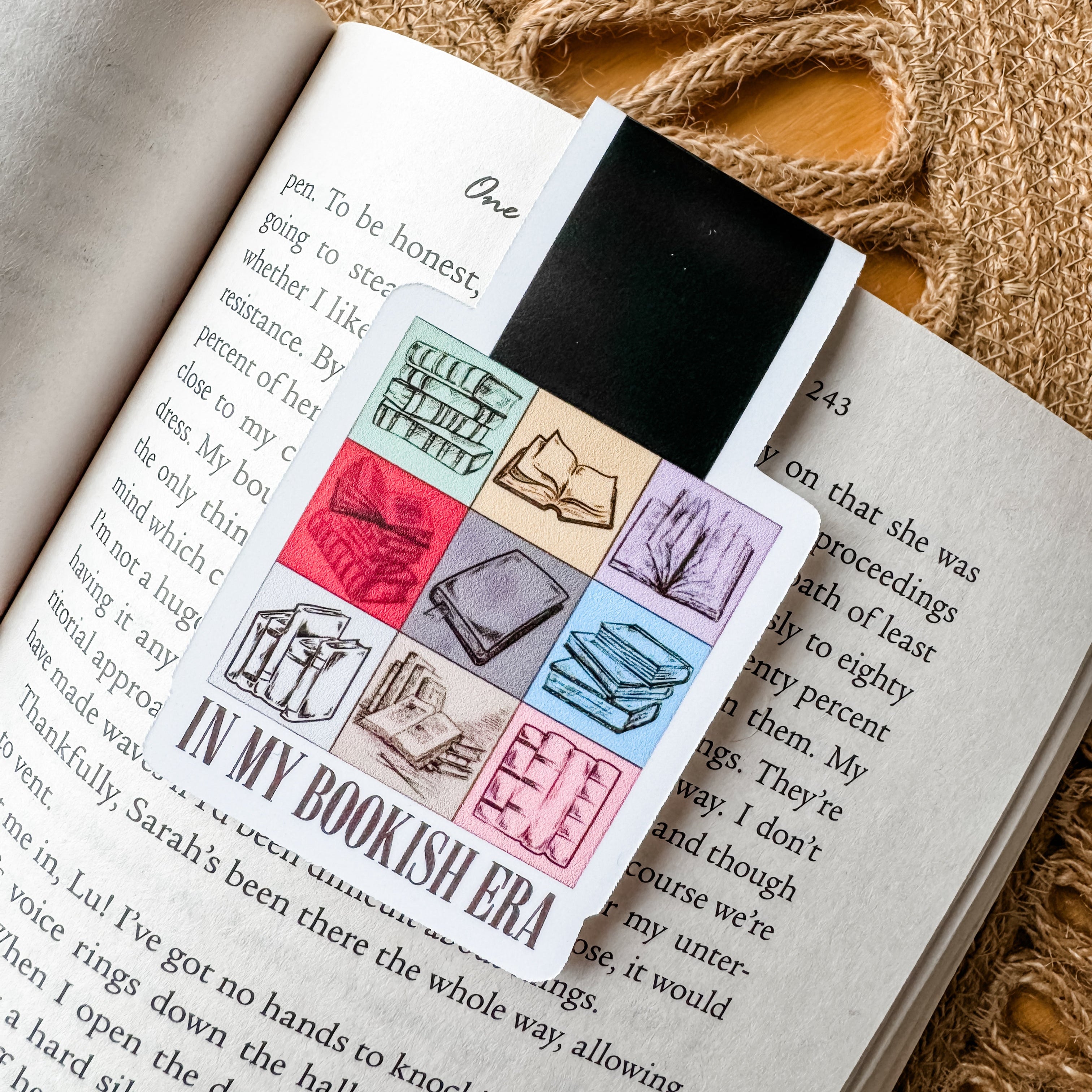 A magnetic bookmark with a colorful bookish design placed on an open book.