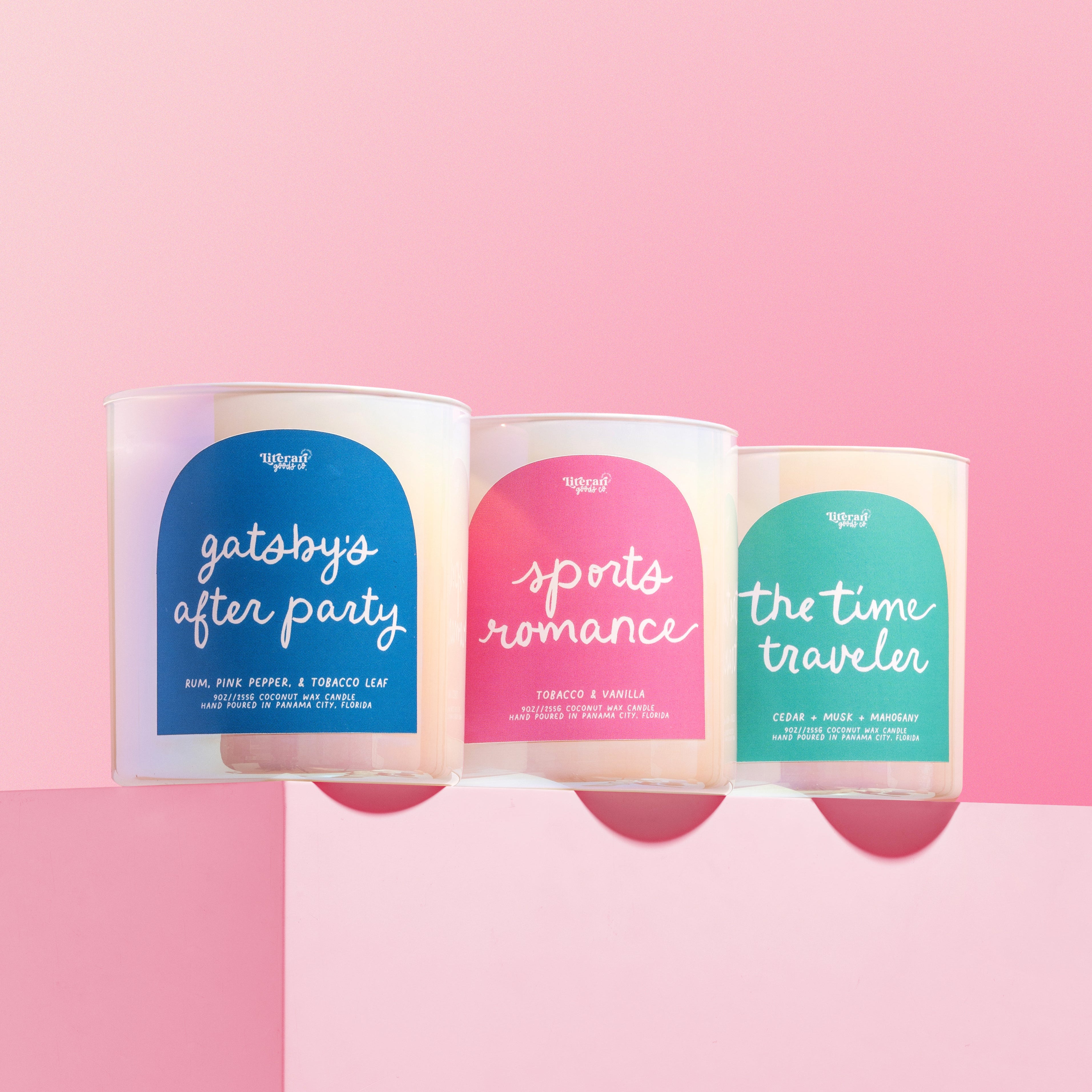 Three book themed candles with colorful labels on a pink background