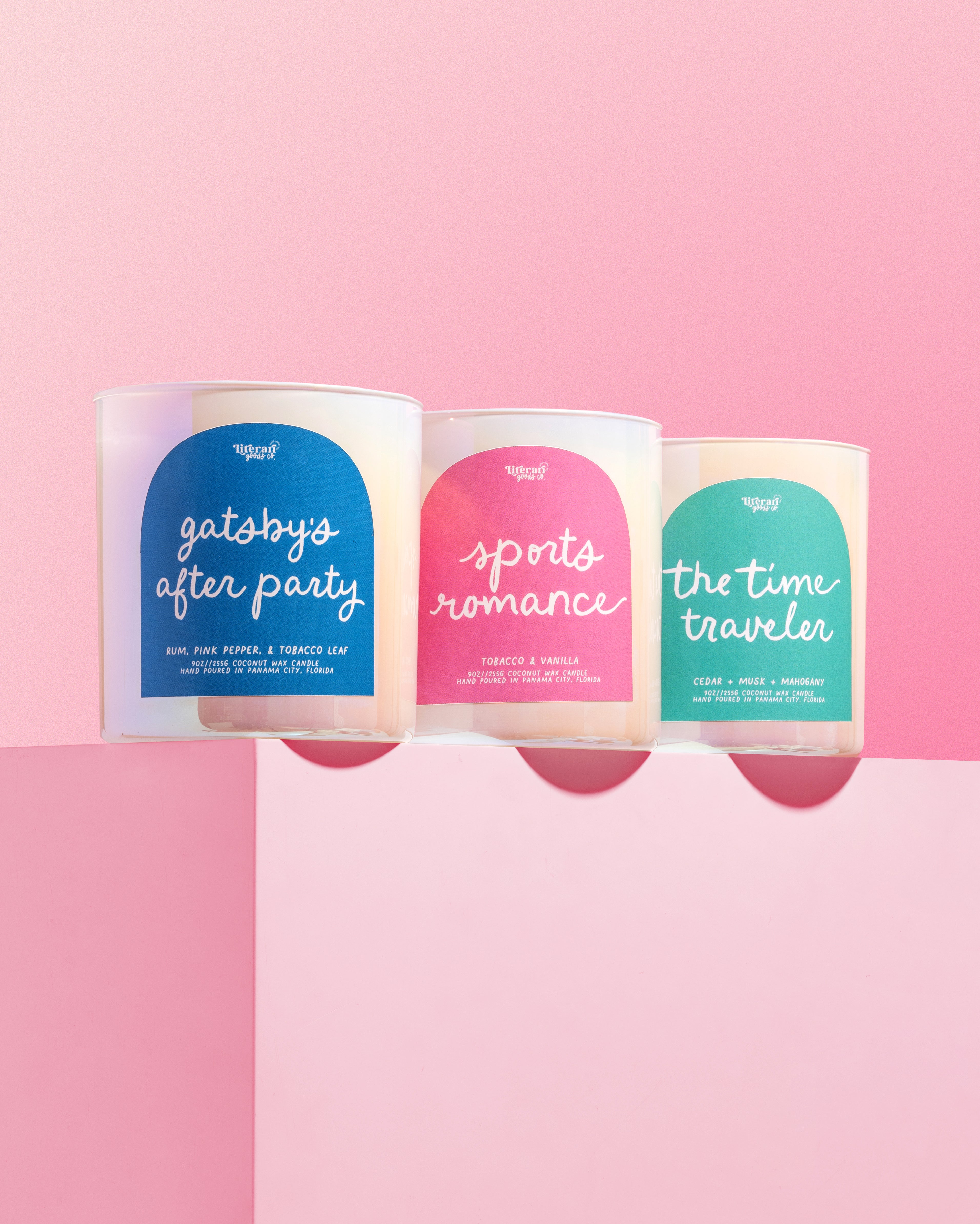 Three book themed candles with colorful labels on a pink background
