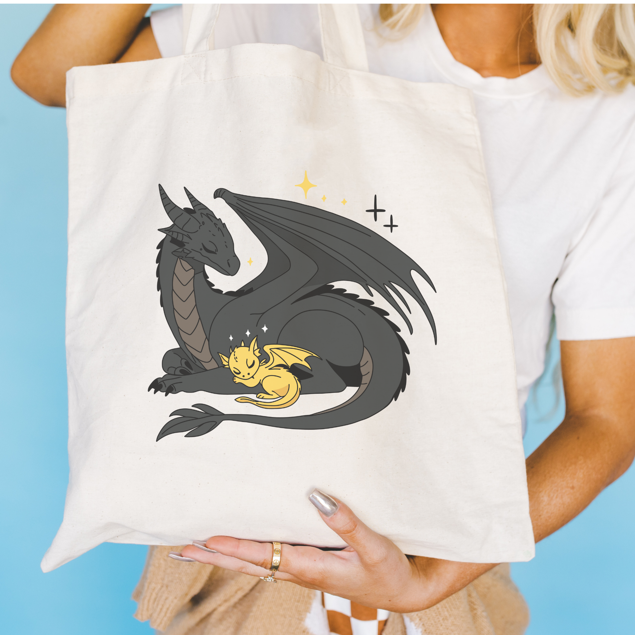 Bookish Person holding a tote bag with a dragon design against a blue background