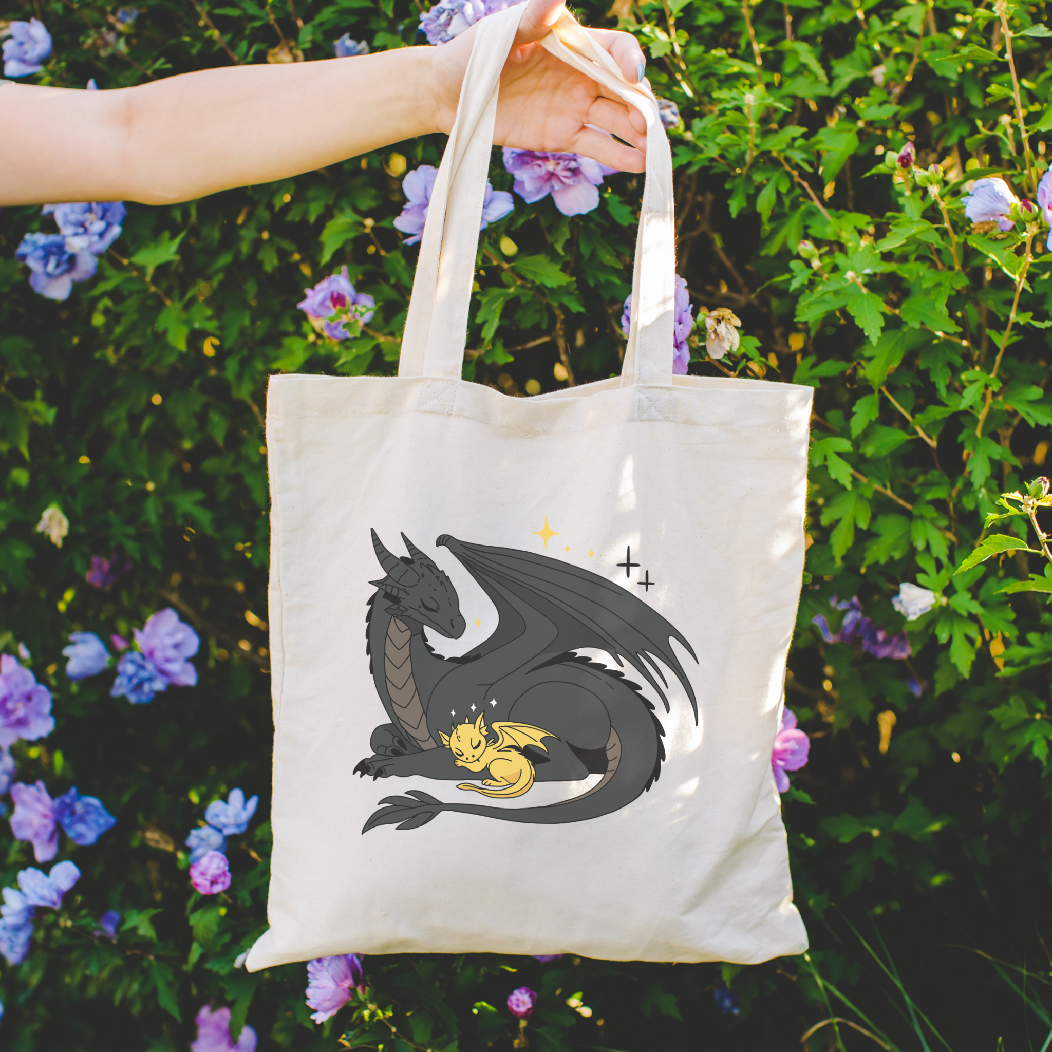 Bookish Tote bag with dragon design held in front of a floral background