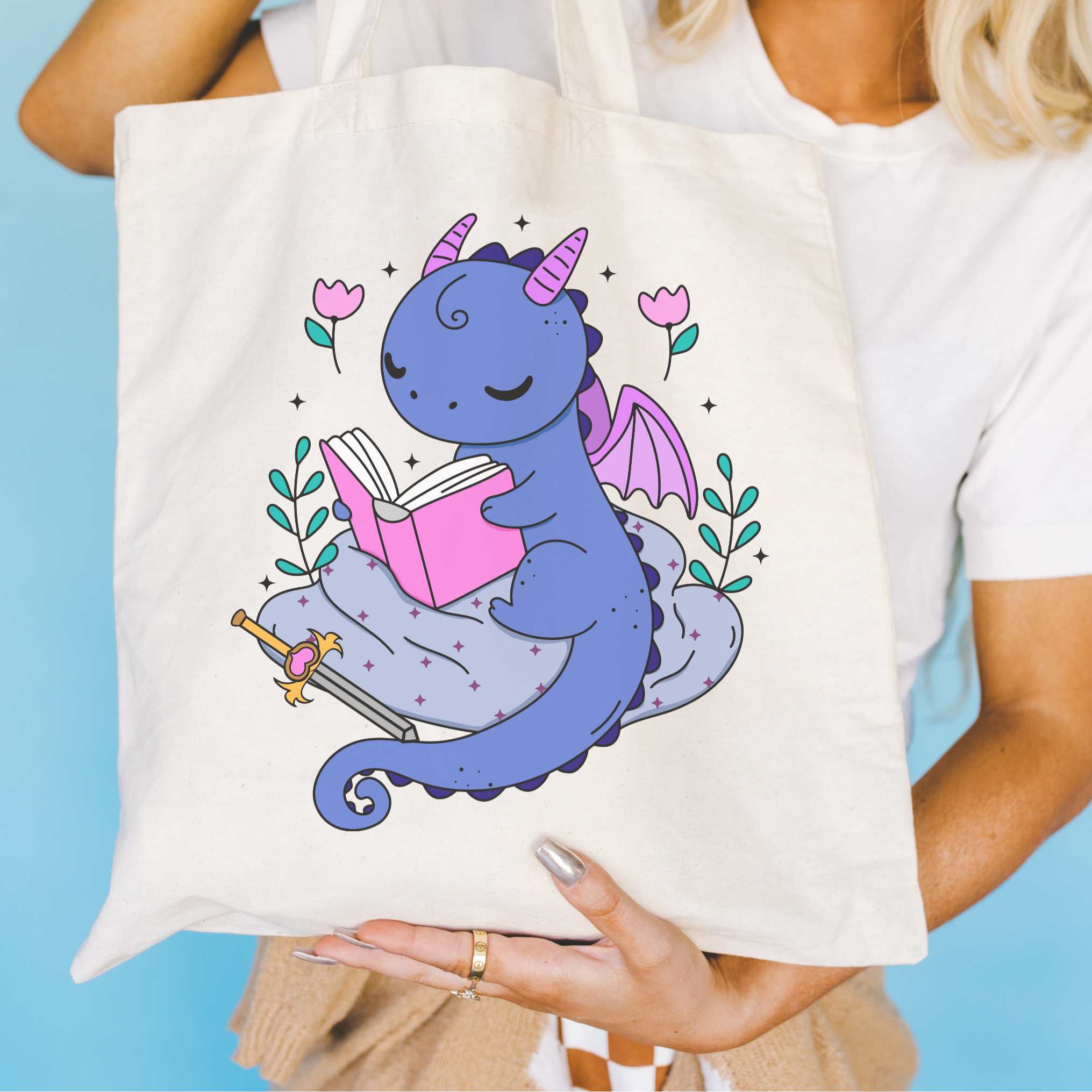 Bookish Tote bag with a dragon design holding a book against a blue background