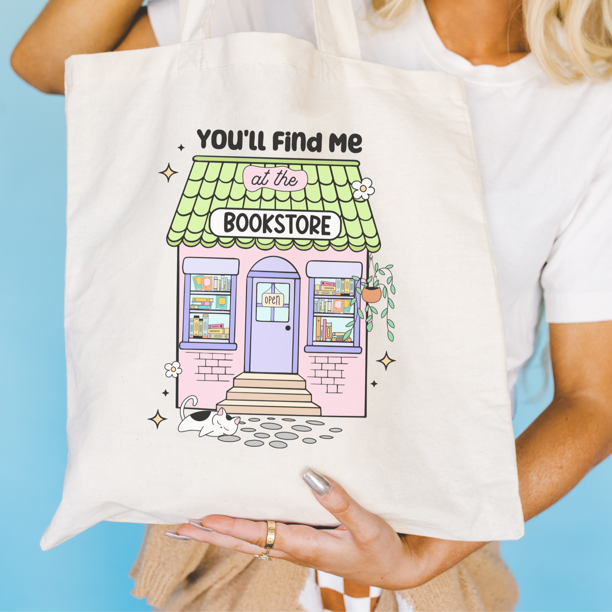 Bookish Tote bag with a bookstore illustration and text held by a person against a blue background
