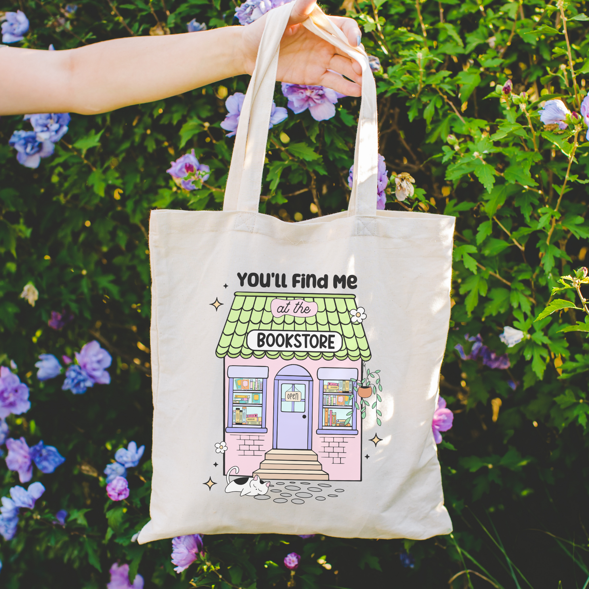 Bookish Tote bag with a bookstore illustration held in front of flowers