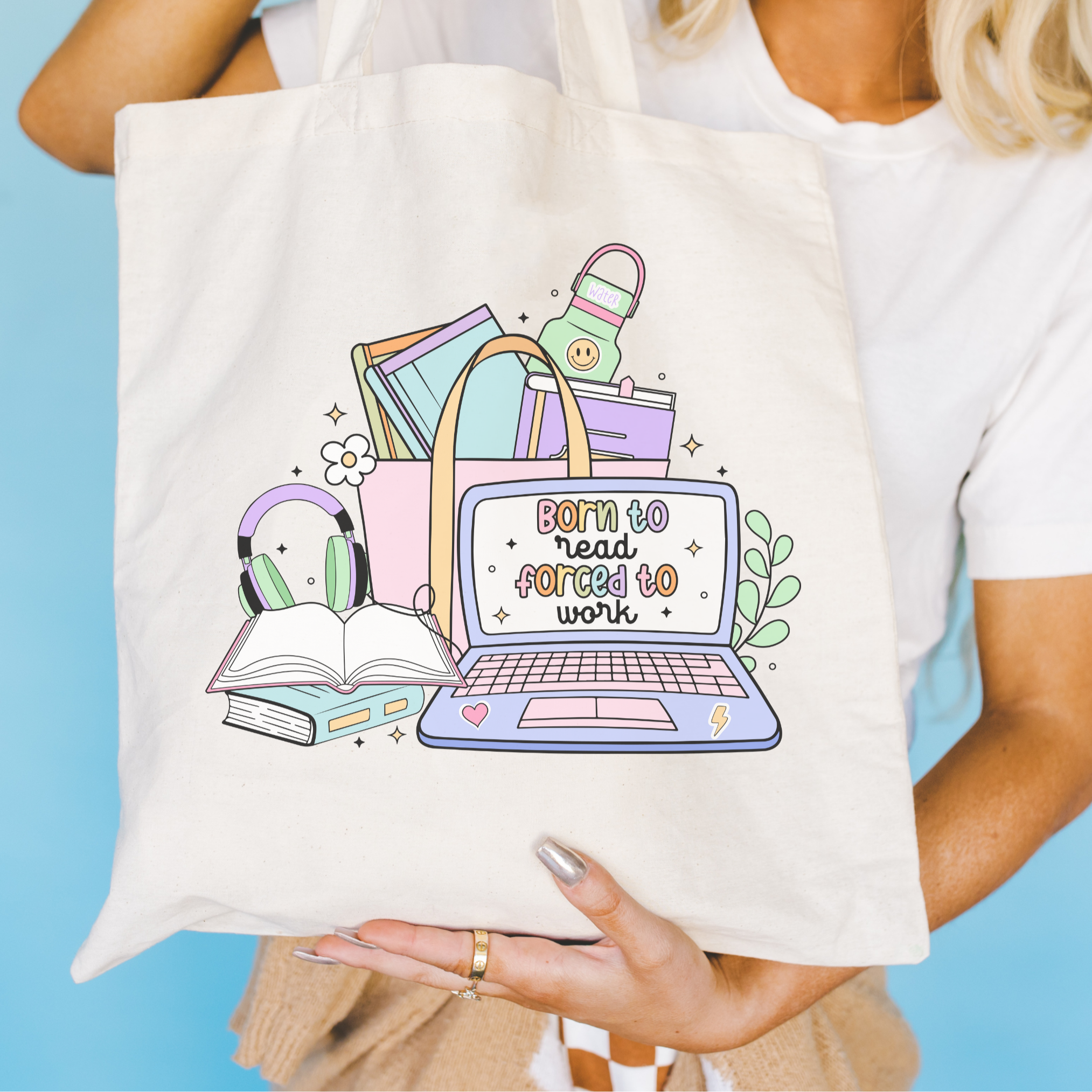 Tote bag with a colorful design of a laptop, books, and headphones, held by a person against a blue background.