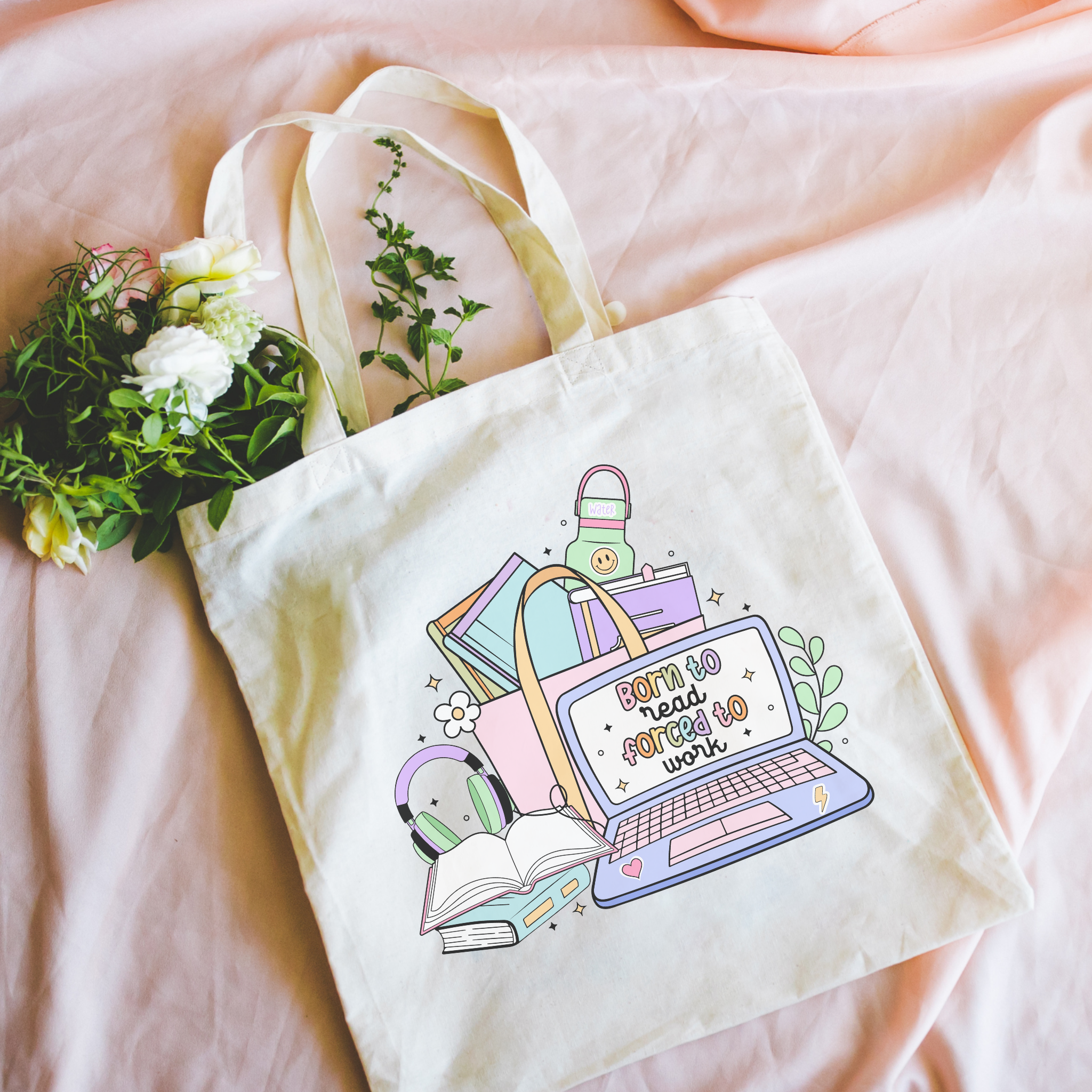 Tote bag with a design of a laptop, books, and flowers on a pink surface.