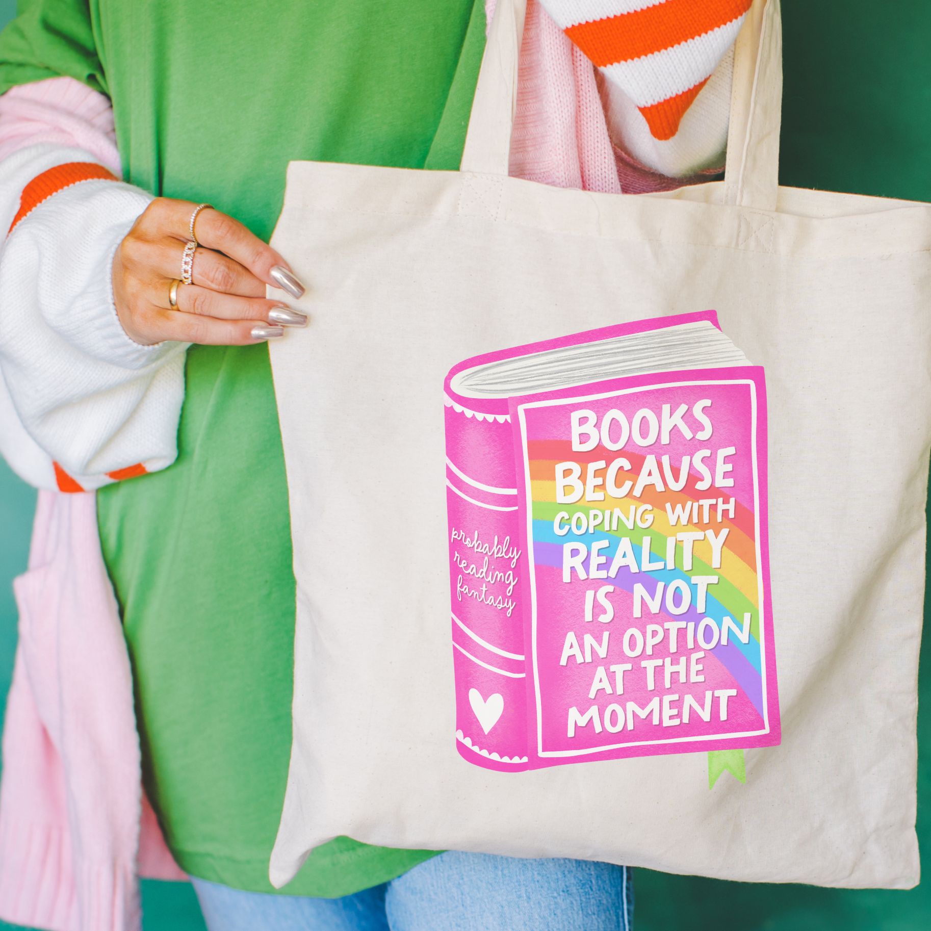 Person holding a bookish tote bag with a colorful book design and text.