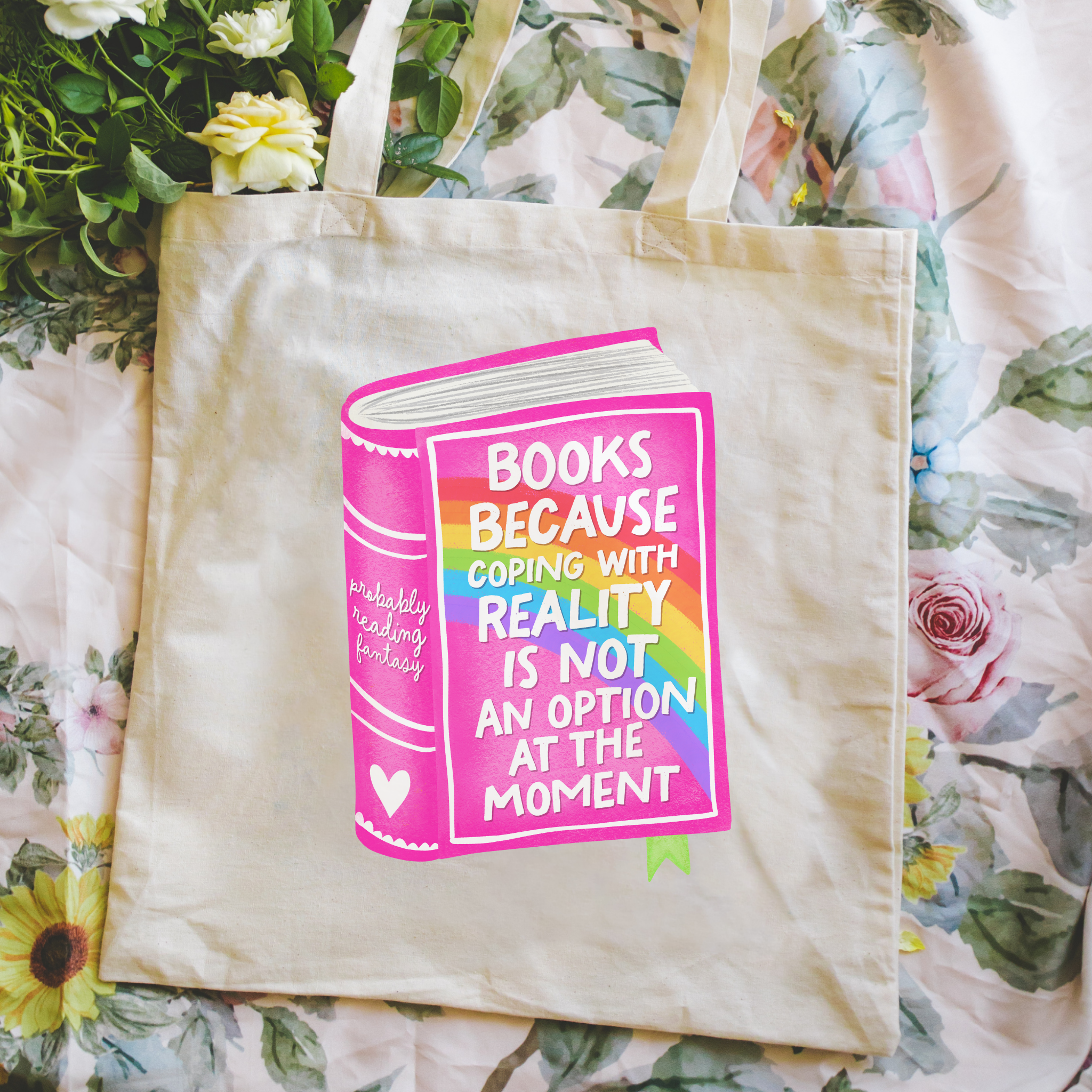 Person holding a bookish tote bag with a colorful book design and text.