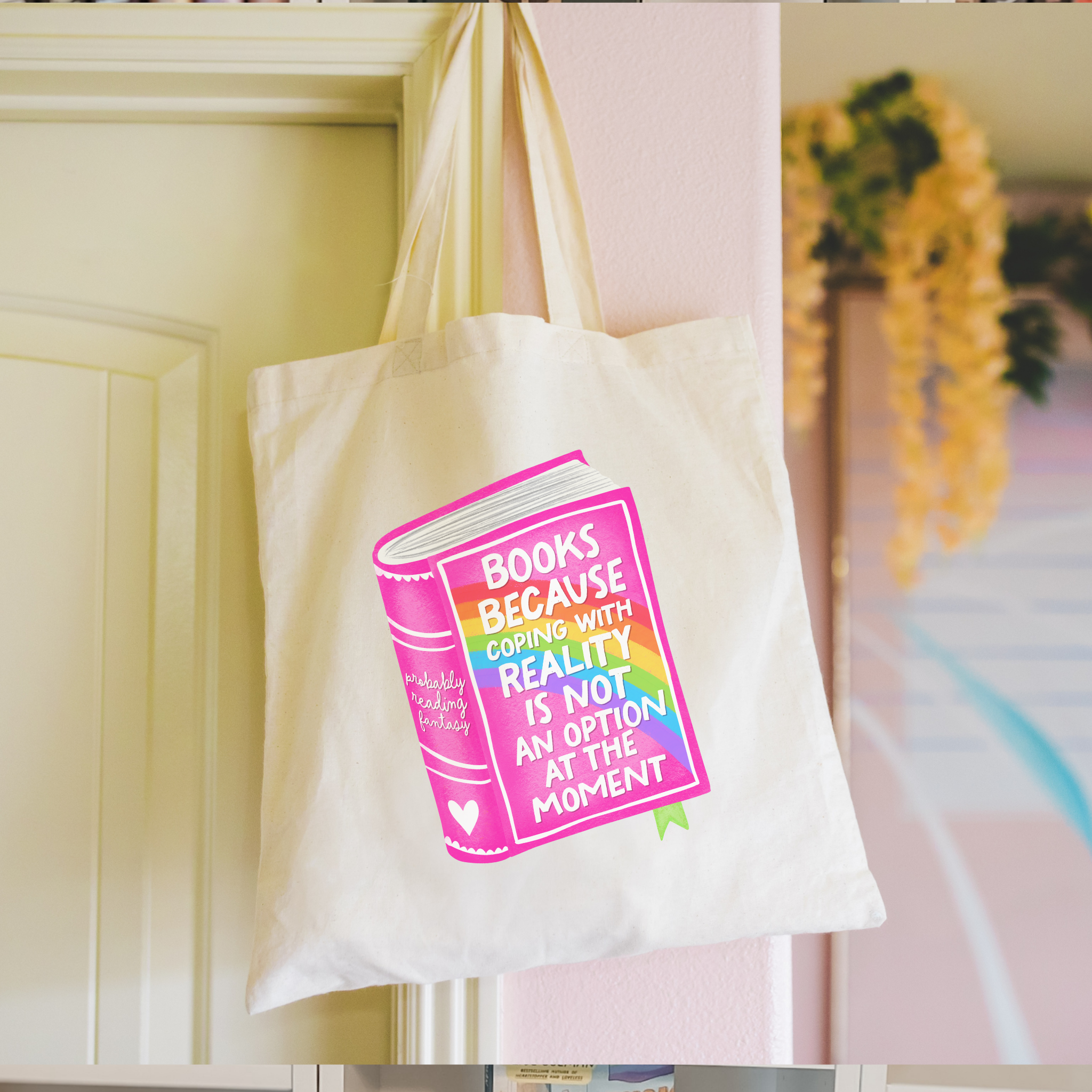 Person holding a bookish tote bag with a colorful book design and text.