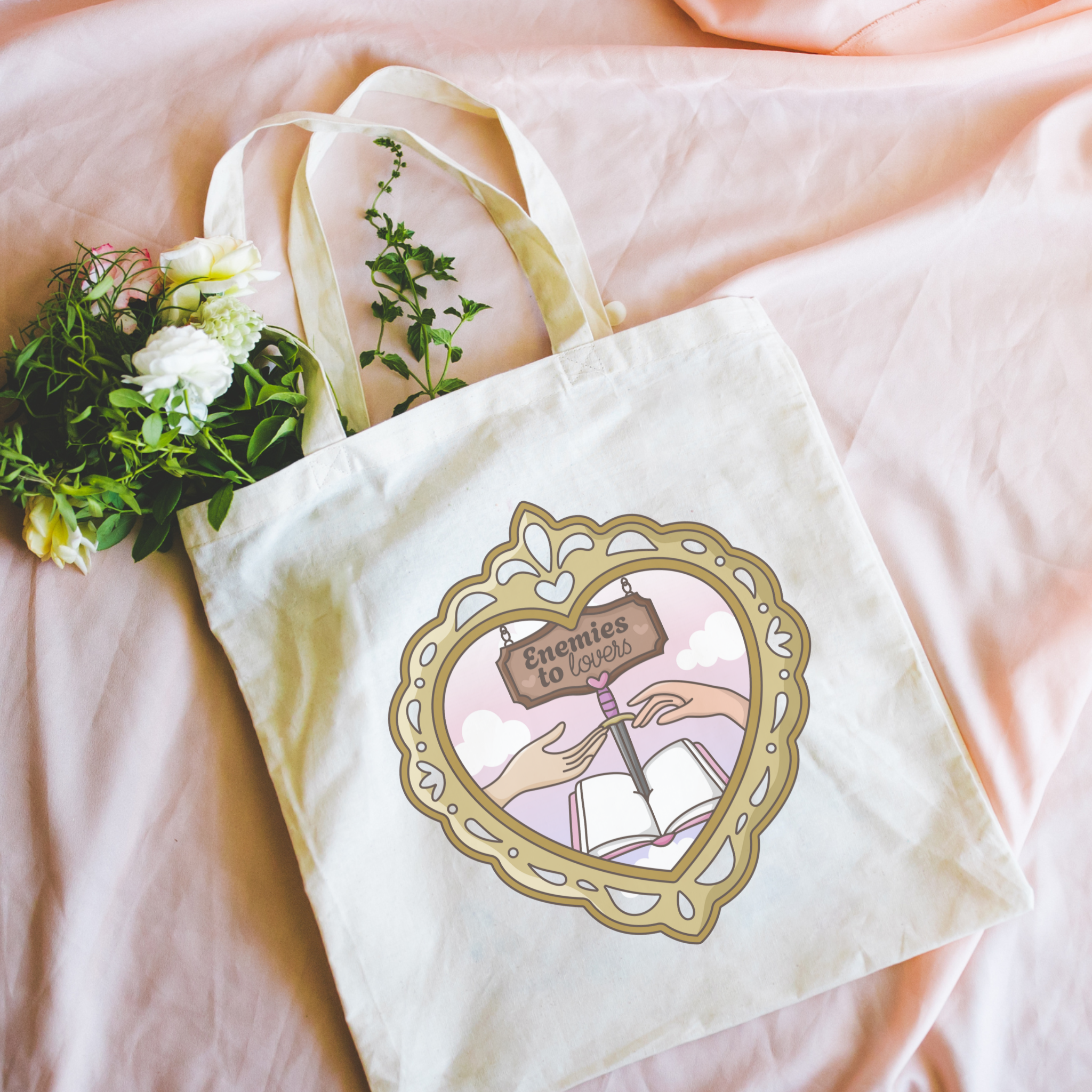 Tote bag with decorative design featuring hands, an open book, and "Enemies to Lovers" on a pink background