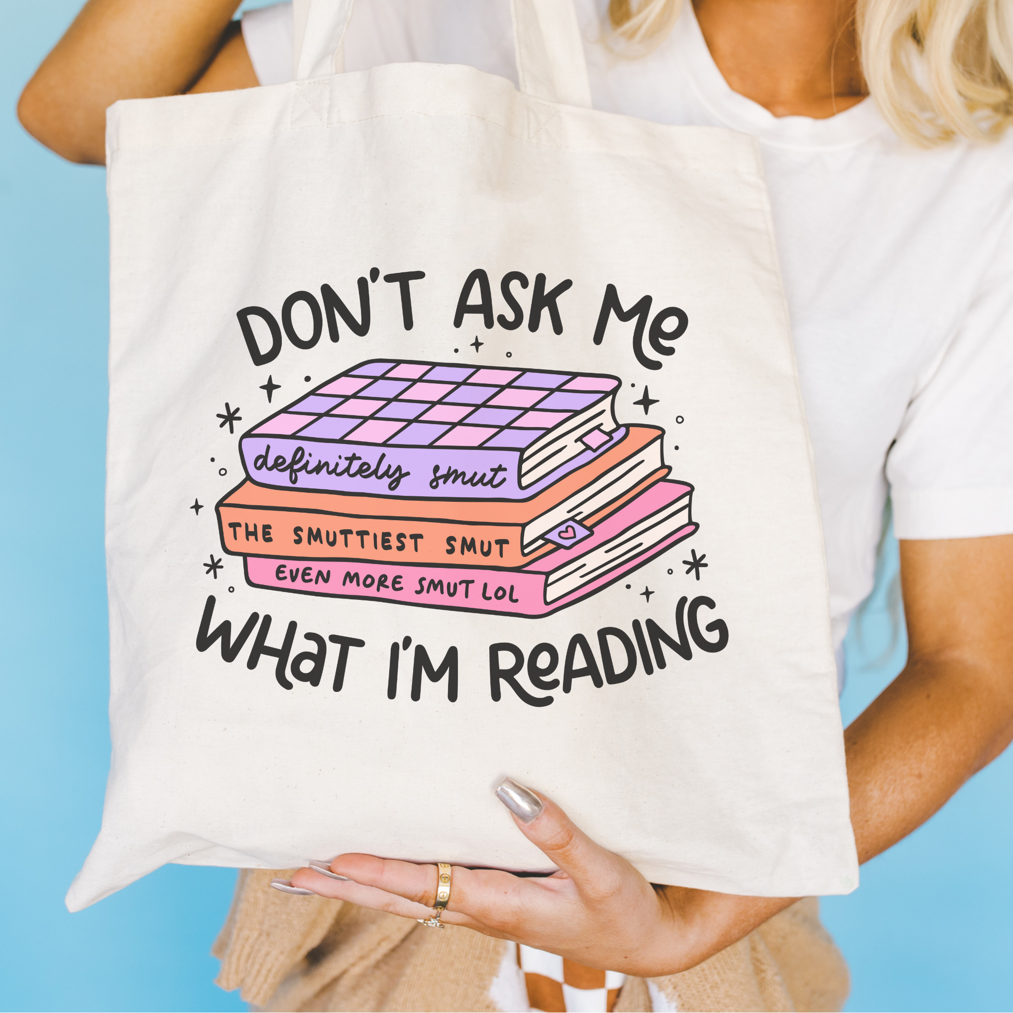 Tote bag with book-themed text held by a person against a blue background