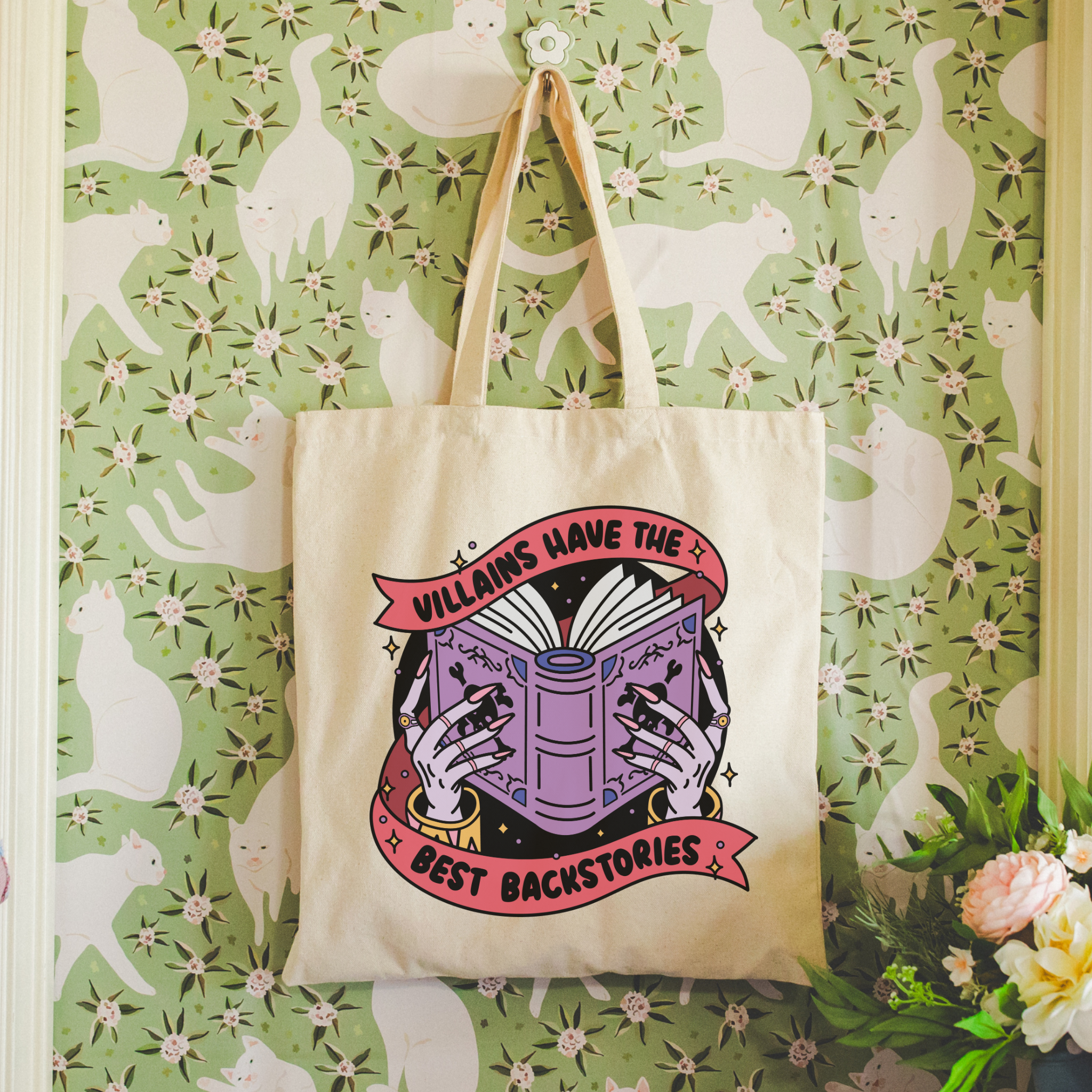 bookish Tote bag with book-themed design against a wallpapered wall with cat pattern