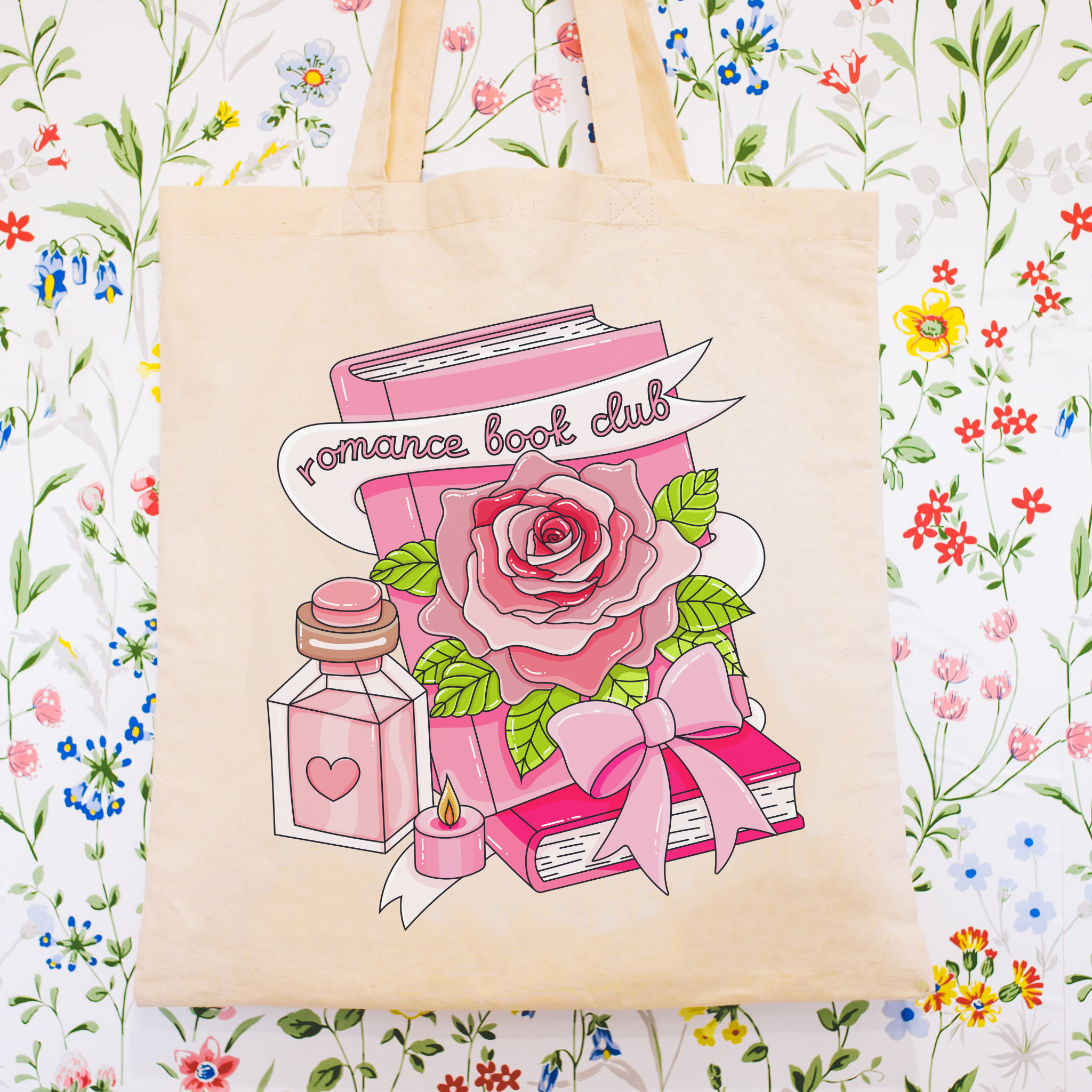 Tote bag with romance book club design featuring a book, rose, and perfume bottle on a floral background.