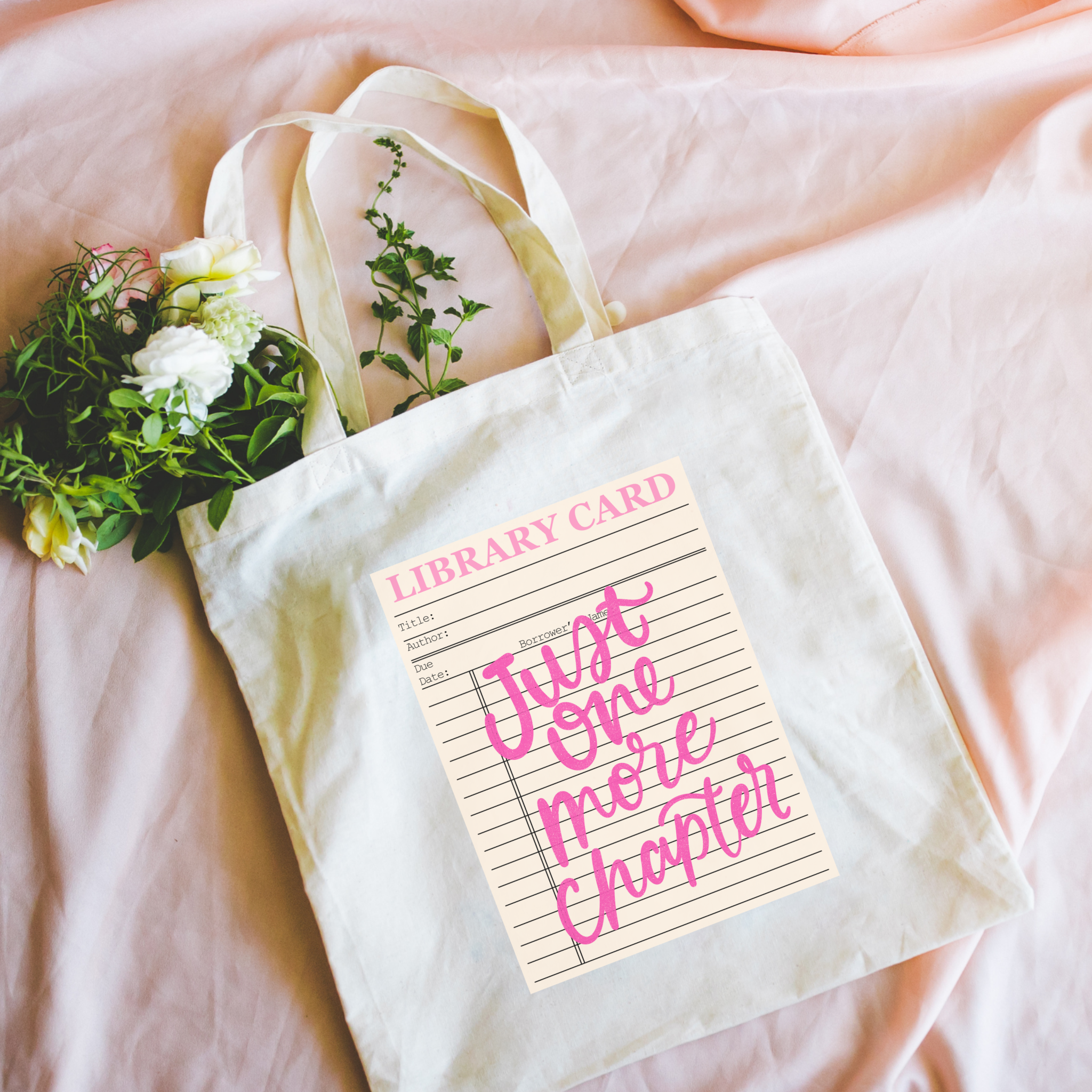 bookish Tote bag with 'Just One More Chapter' design on a pink surface with flowers.