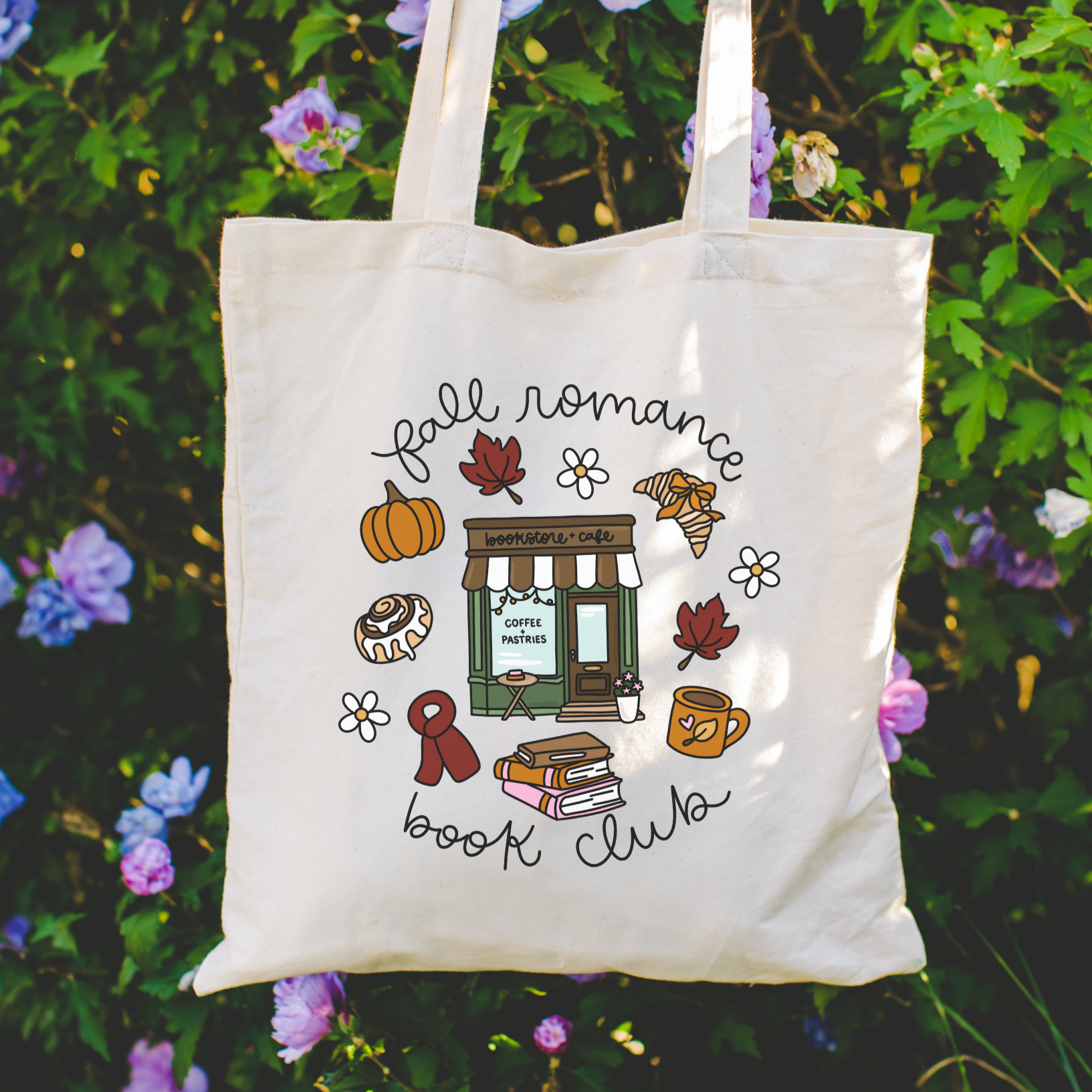 Bookish Tote bag with 'Fall Romance Book Club' design held in front of a floral background