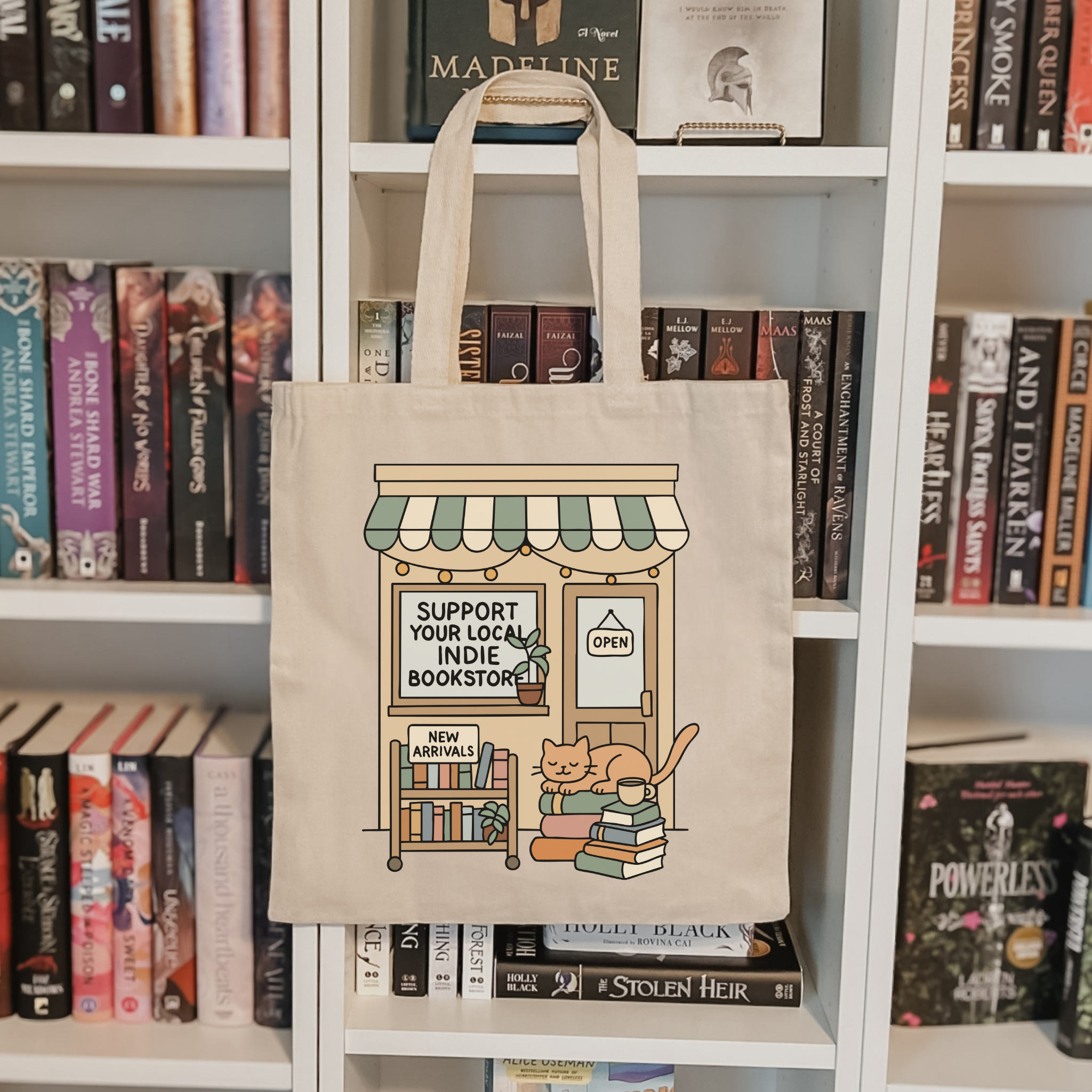 Tote bag with a bookstore illustration hanging on a bookshelf with books around