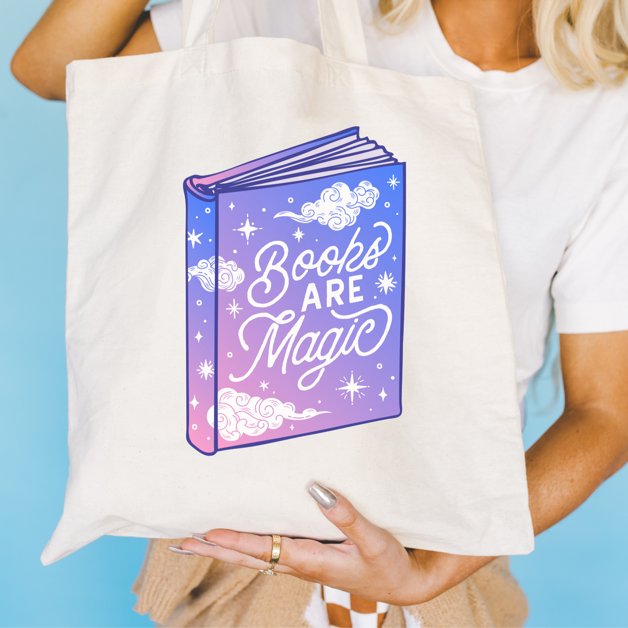 Tote bag with 'Books Are Magic' design held by a person against a blue background