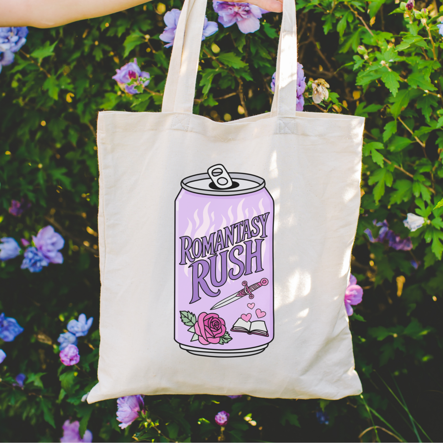 Bookish tote bag with 'Romantasy Rush' design held in front of a floral background