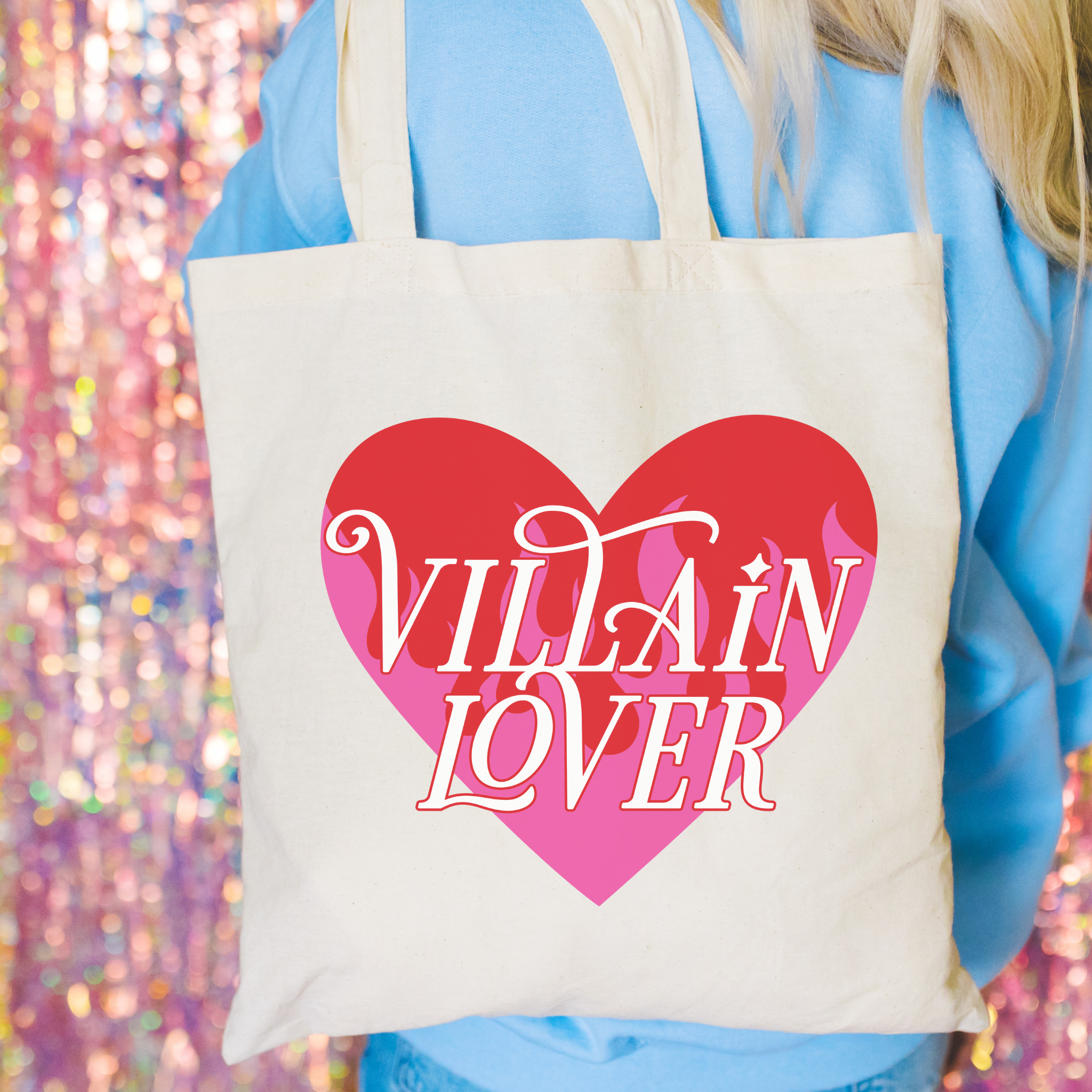 Tote bag with 'Villain Lover' design held by a person against a colorful, blurred background