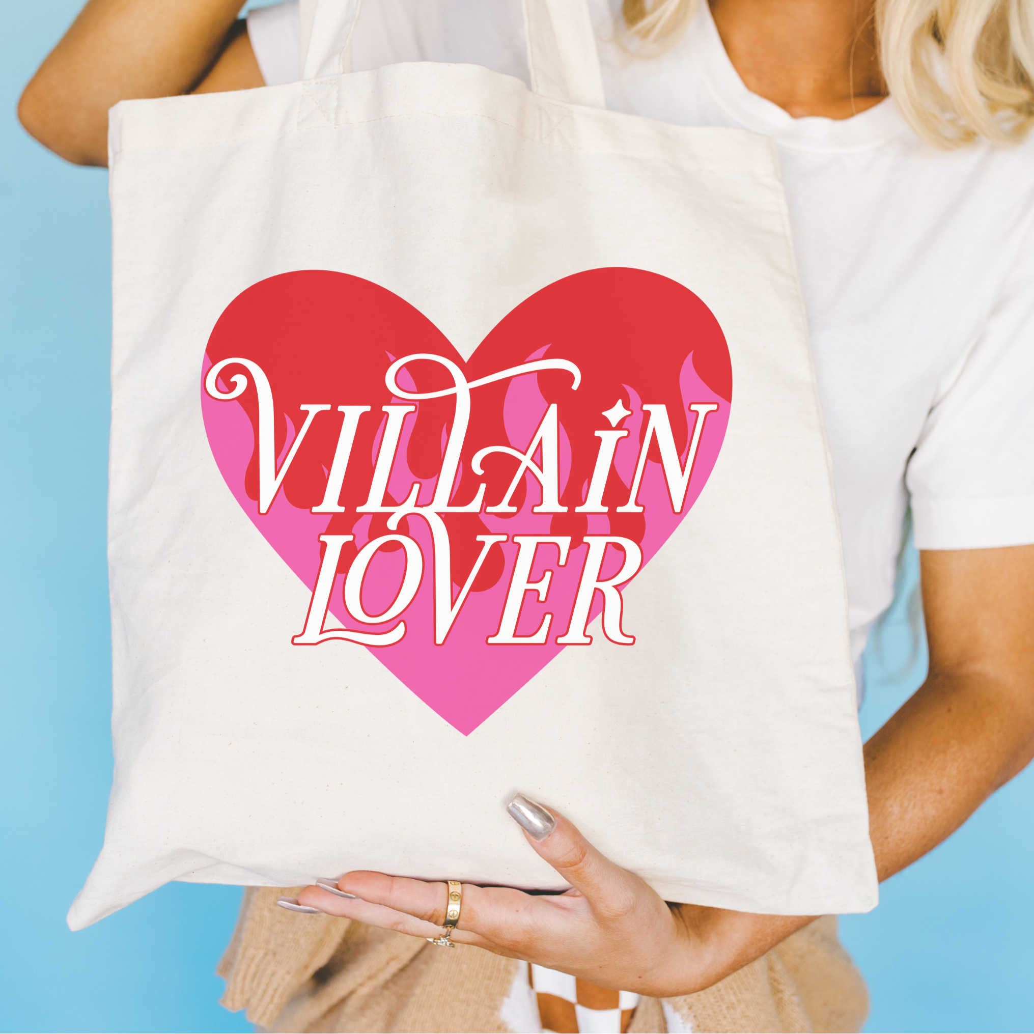 Tote bag with 'VILLAIN LOVER' design held by a person against a blue background