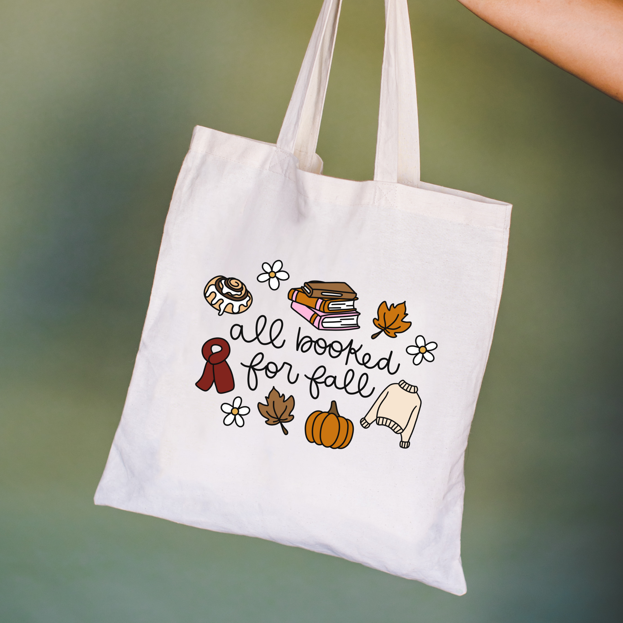 Bookish tote bag with autumn-themed illustrations and text on a green background with text "all booked for fall"