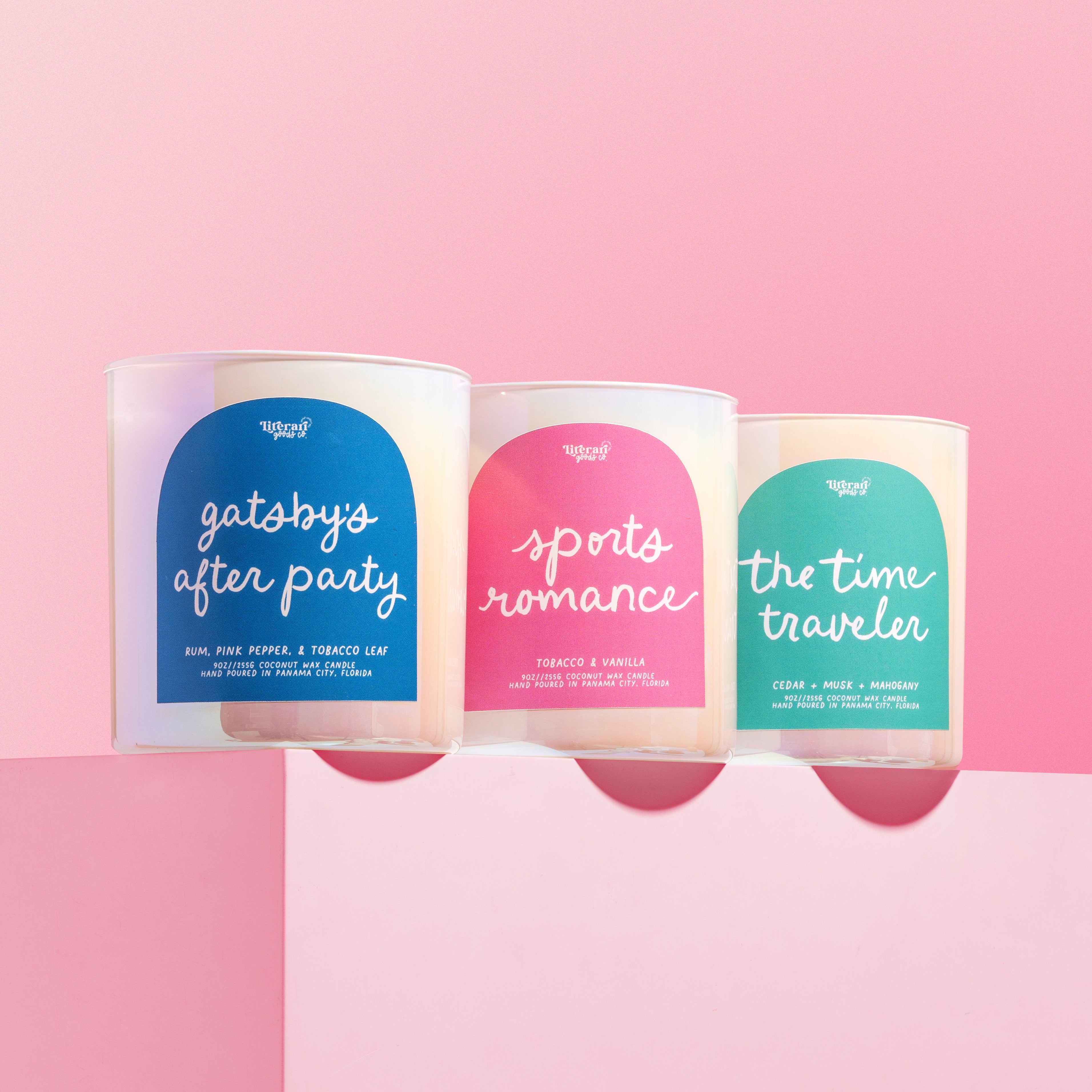 Three book inspired candles with colorful labels on a pink background