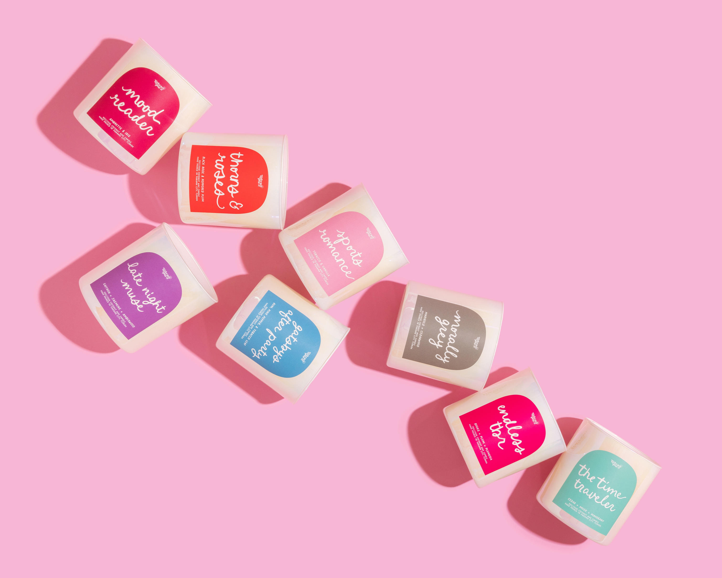 Assorted  bookish candles for readers with colorful labels on a pink background that make great gifts for book lovers, swifties, teachers, and students.