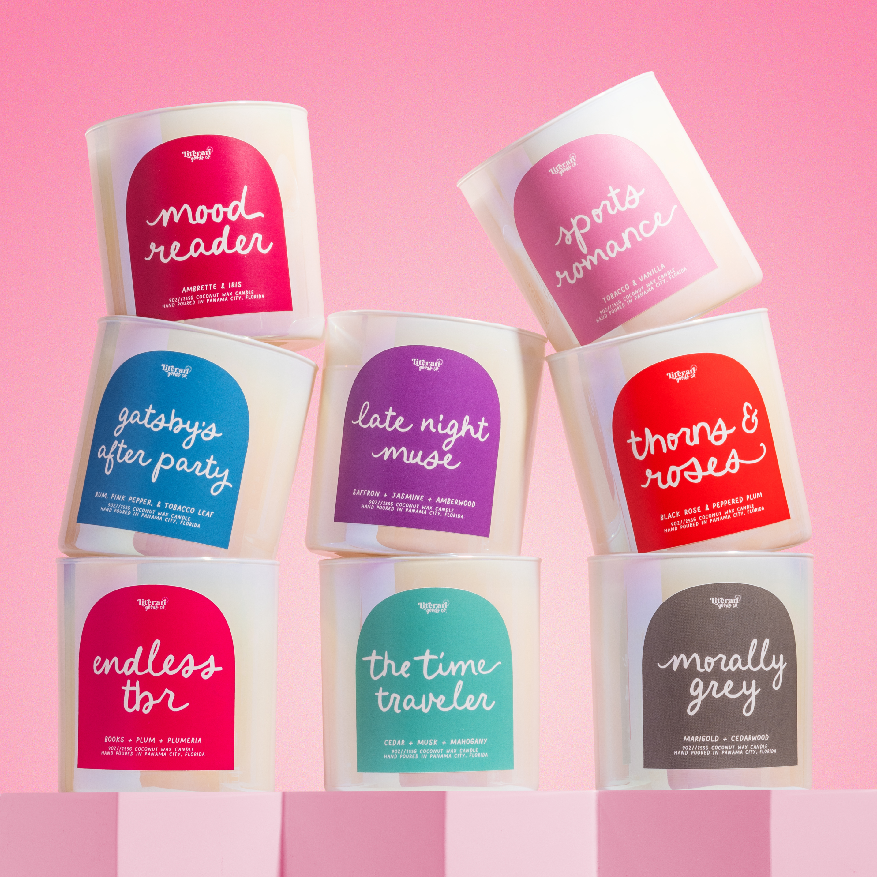 Set of bookish candles with colorful labels on a pink background